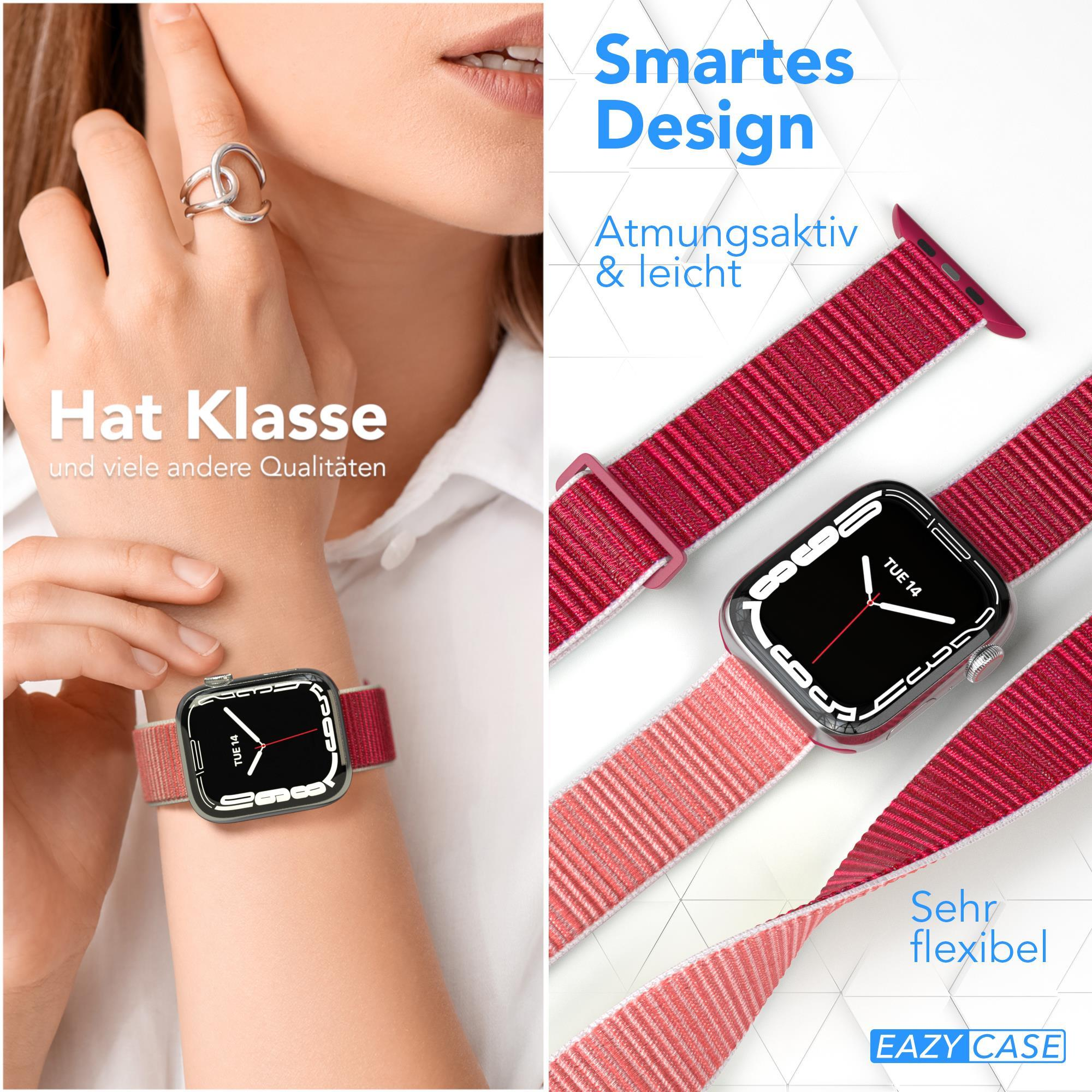 Eine Person trägt eine Uhr mit rotem Armband. Die Uhr zeigt 'TUE 14'. Nahaufnahme des Armbands.