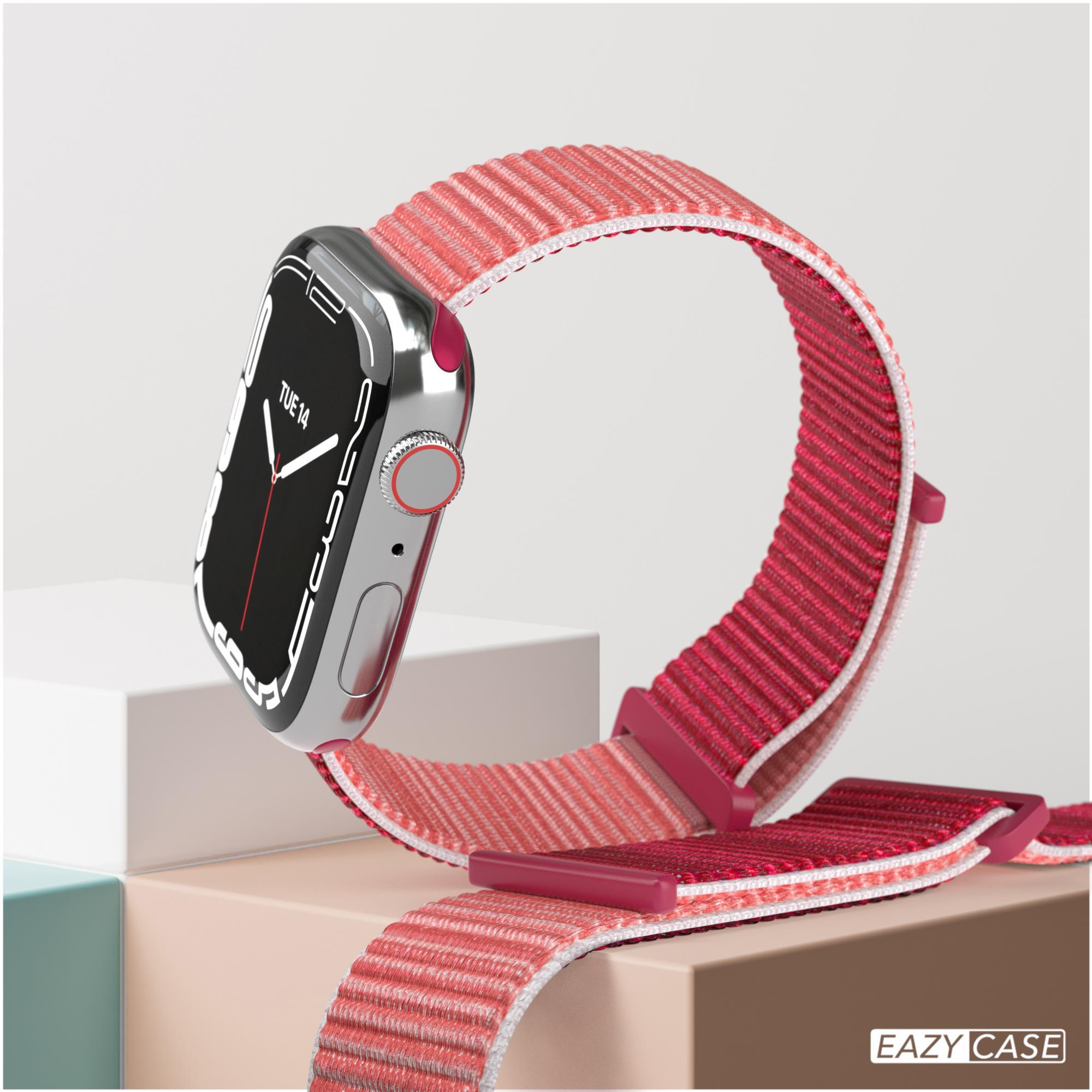 Silberne Apple Watch mit rotem Armband. Sie liegt auf einer hellen Oberfläche.