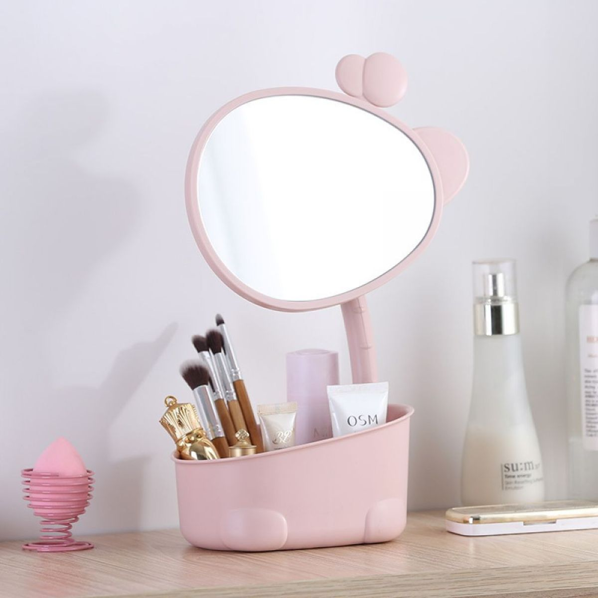 Rosa Make-up-Organizer mit Spiegel, Bürsten und Schönheitsprodukten auf Holz.