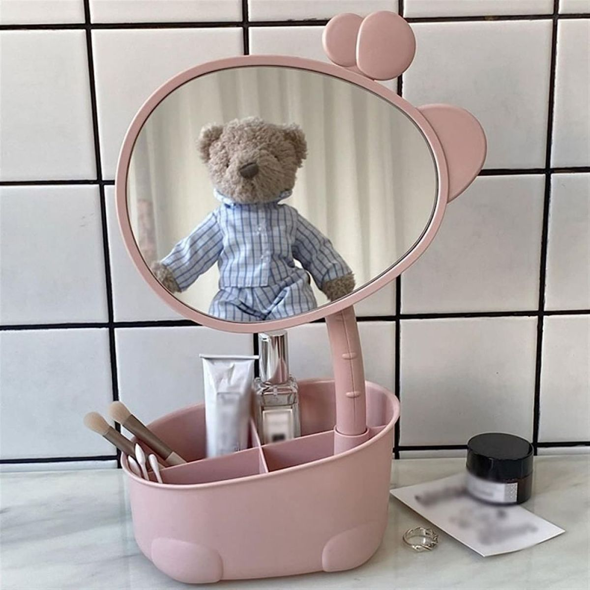 Rosa Schminkspiegel mit Teddybär und Make-up-Produkten.