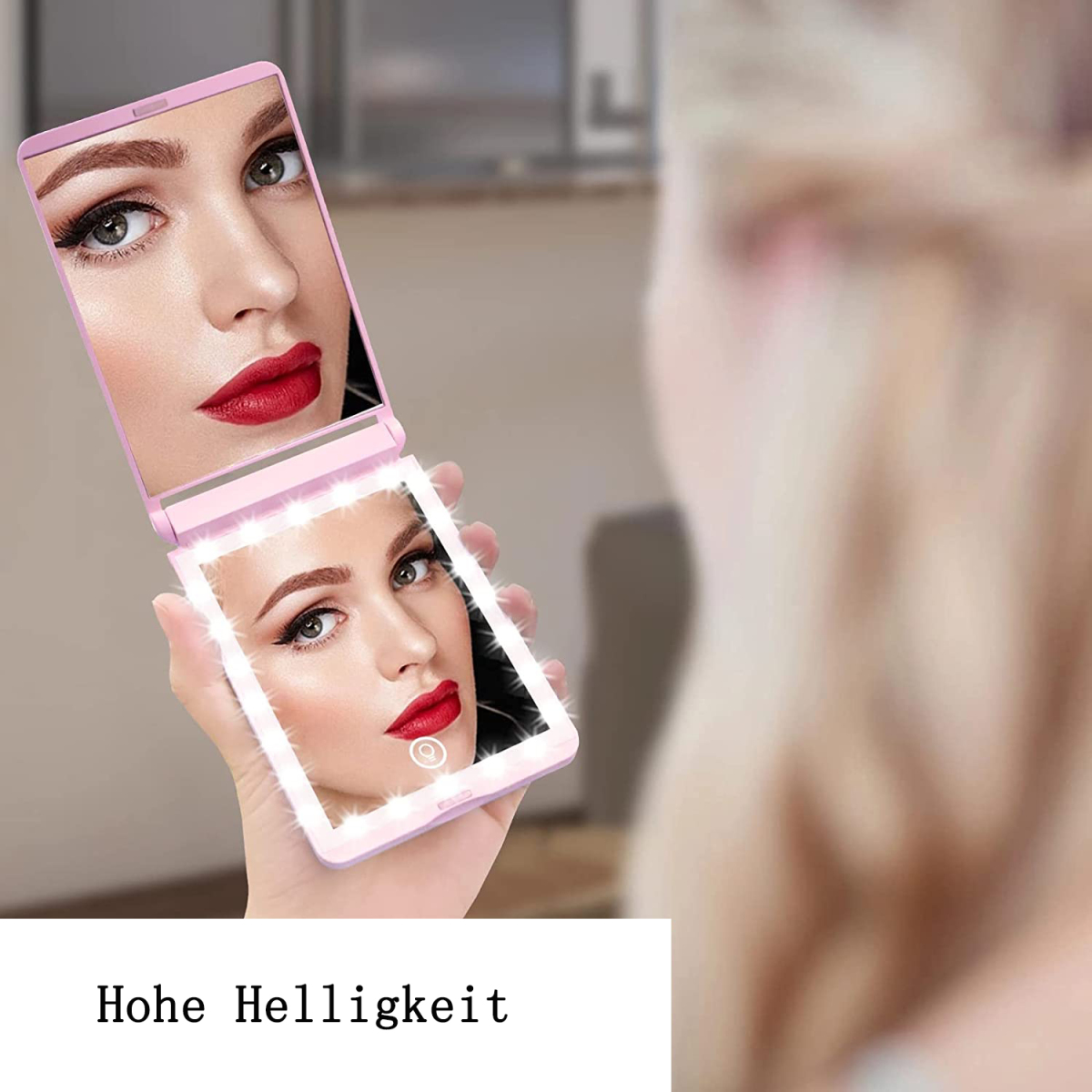 Hand hält einen rosa LED-Spiegel, der eine Frau mit rotem Lippenstift reflektiert. Hintergrund ist eine verschwommene Person.