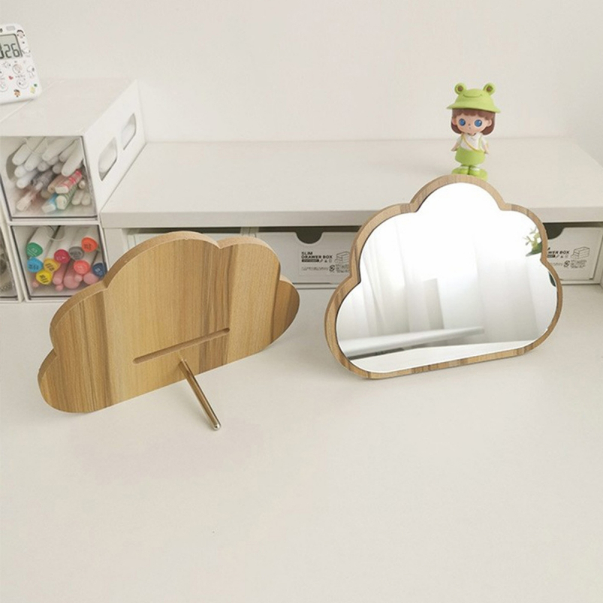Wolkenförmiger Holzspiegel und Ständer auf einem Schreibtisch mit anderen Objekten.