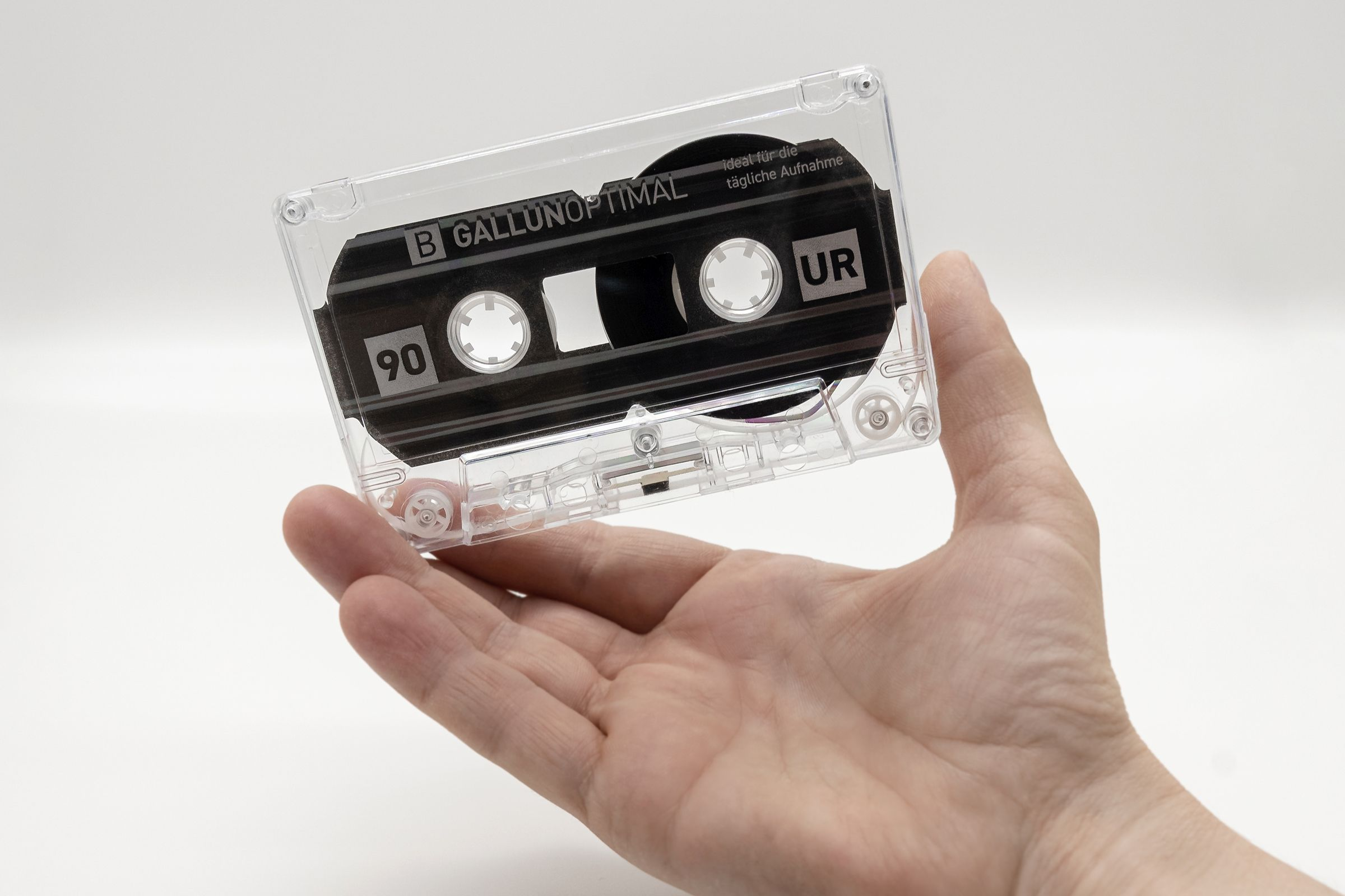 Eine Hand, die eine transparente Kassette mit schwarzem Innenraum hält.