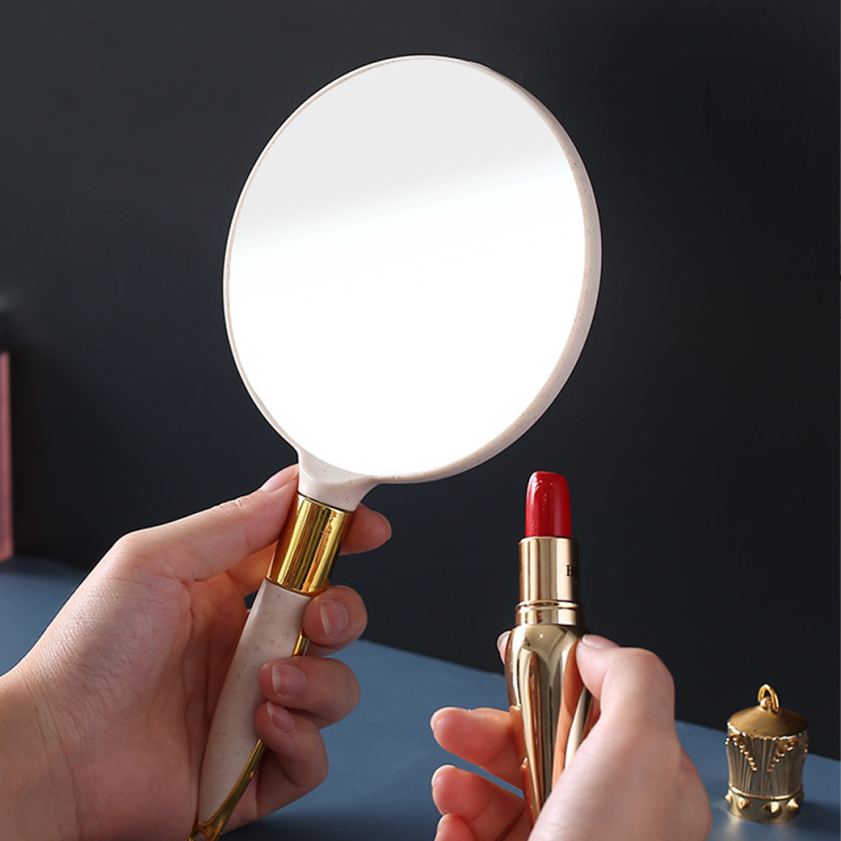 Eine Frau hält Spiegel und Lippenstift, einen roten Lippenstift in der rechten Hand.