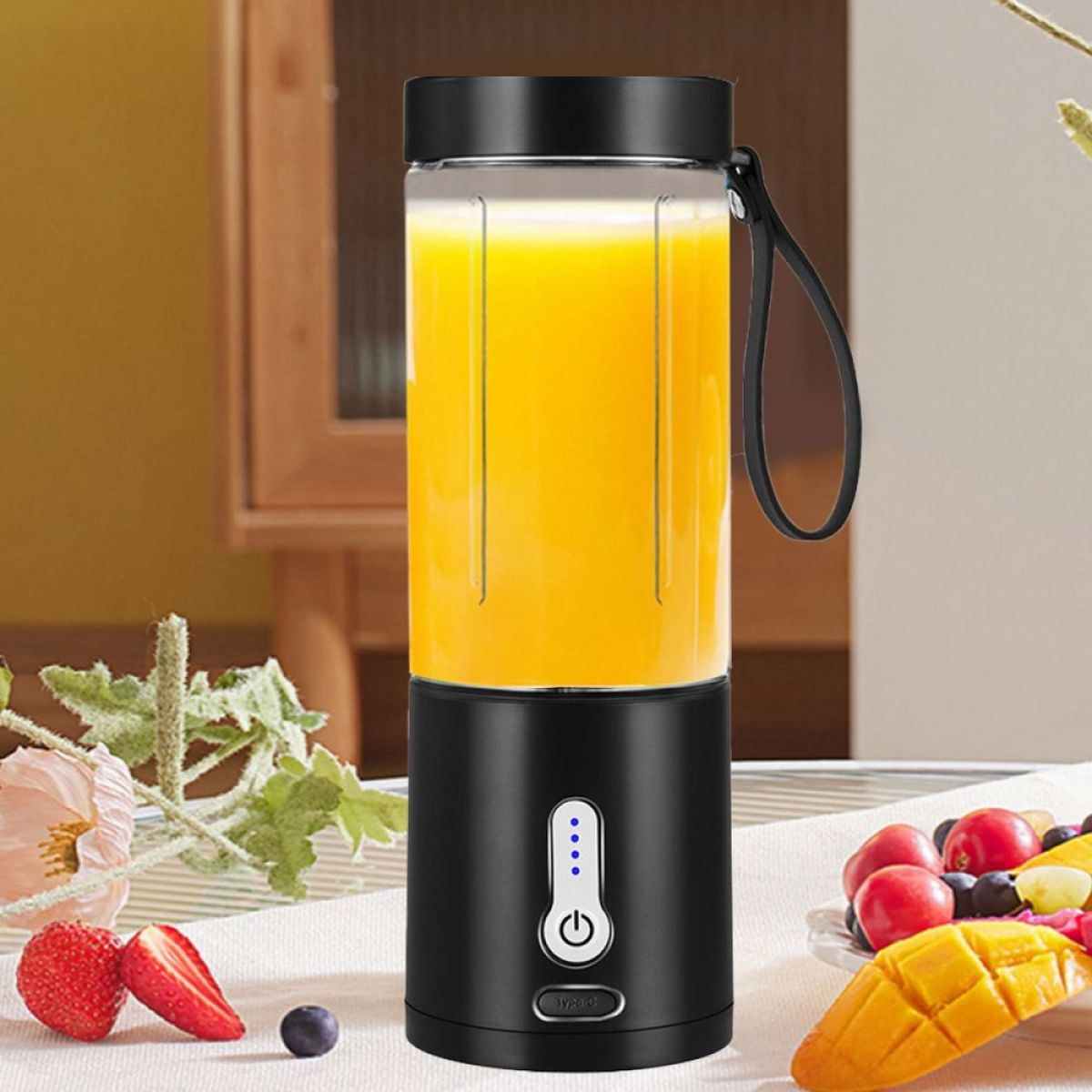 Schwarzer und klarer Mixer mit Orangensaft, Erdbeeren, Mango und einer Beere auf einem Tisch.