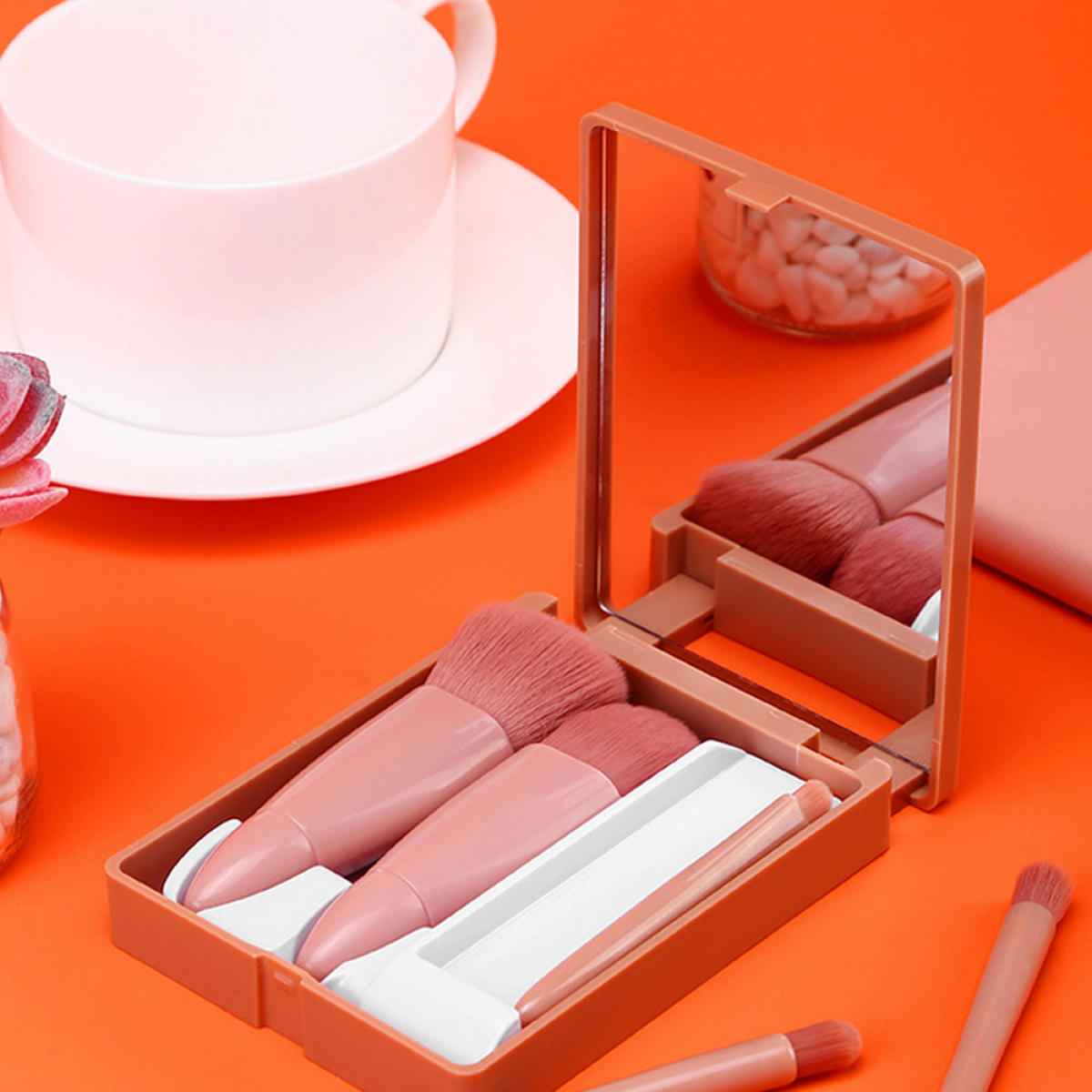 Ein Make-up-Set mit Pinseln und einem Spiegel auf einer orangefarbenen Oberfläche.