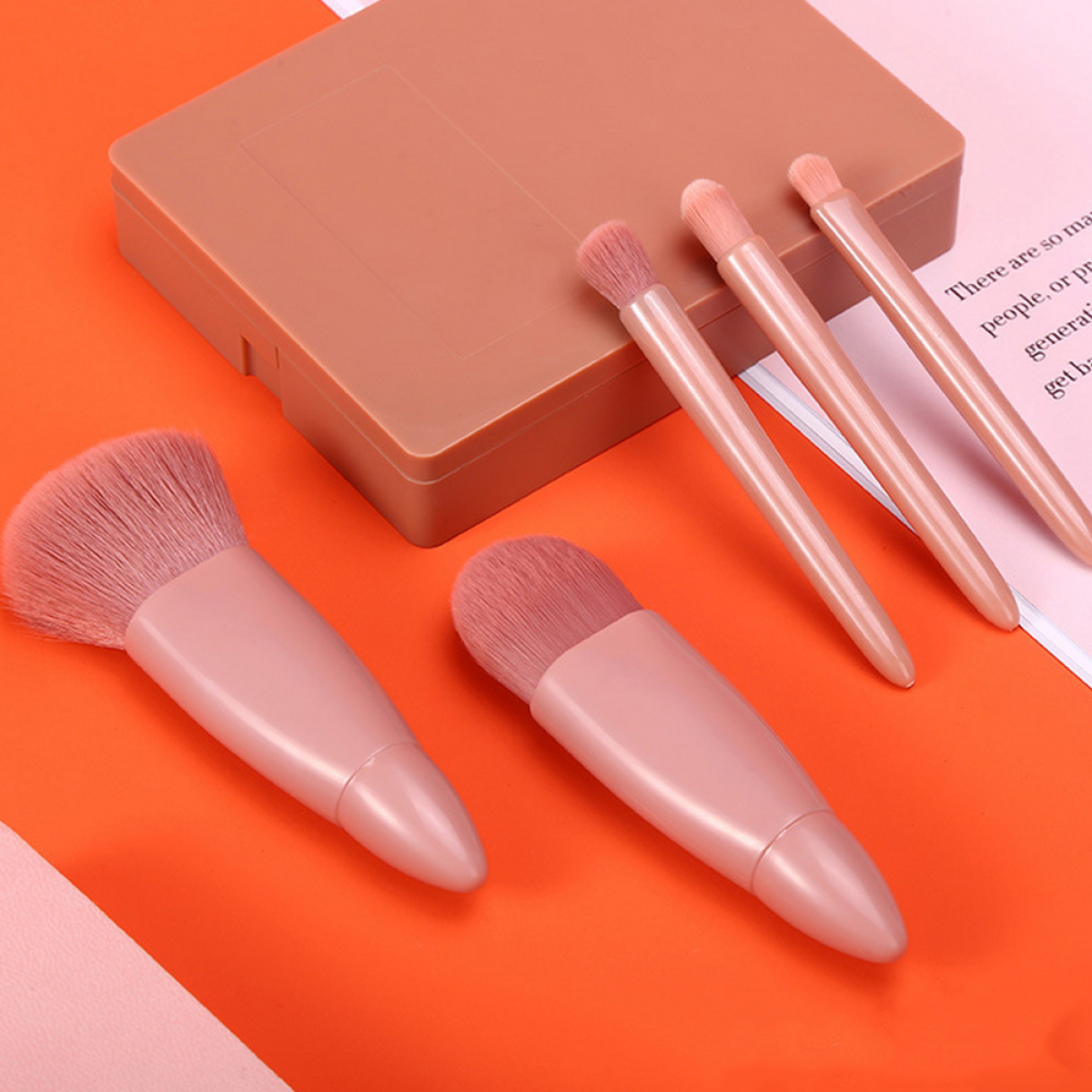 Make-up-Pinsel in Rosatönen auf einer orangen Oberfläche neben einem Make-up-Compact angeordnet.