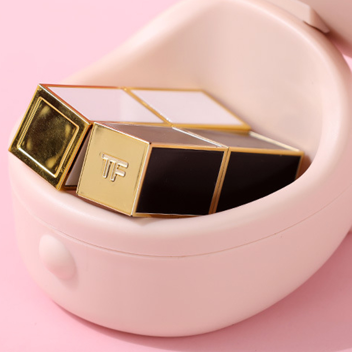 Vier Lippenstifte in einem rosa Halter, mit goldenen und schwarzen Details. Das TF-Logo ist sichtbar.