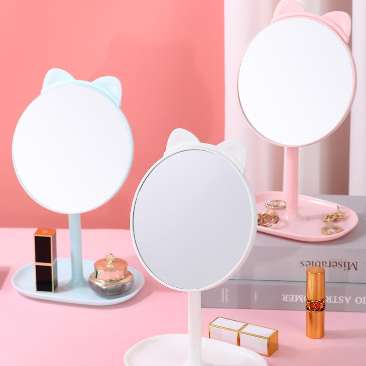 Drei Make-up-Spiegel mit Katzenohren und Make-up-Artikeln auf dem Tisch. Zwei sind blau und einer ist rosa.