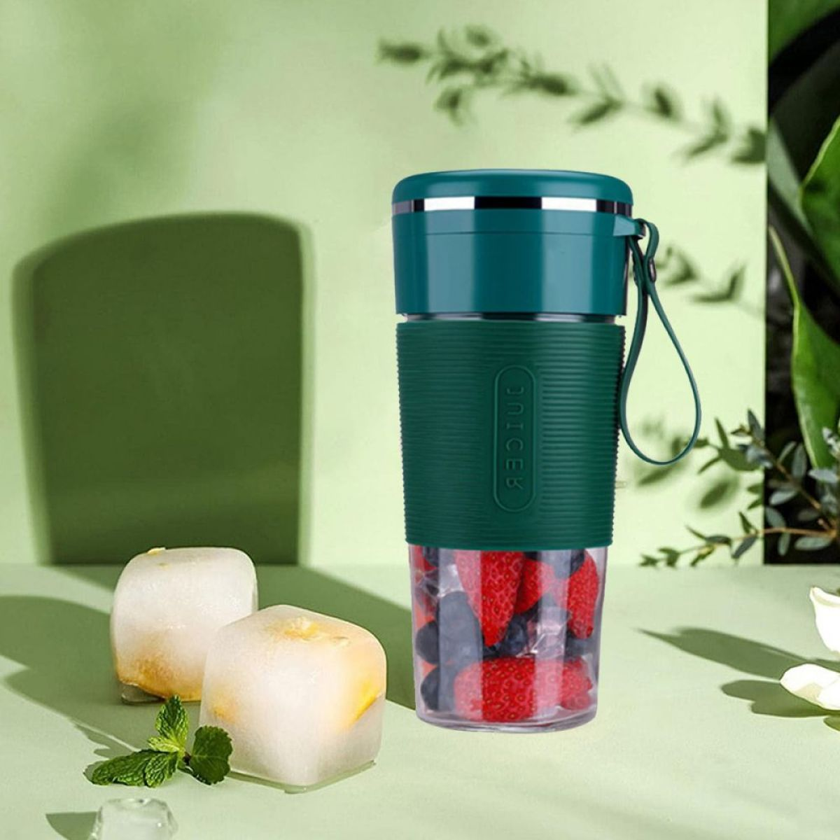 Grüner Mixer mit Eiswürfeln und Beeren auf grünem Hintergrund.
