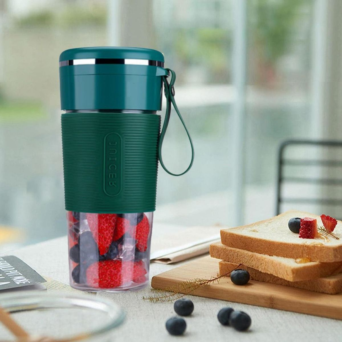 Grüner Mixer mit Beeren und Brot, und Brotscheiben. Beeren und Brot sind davor.