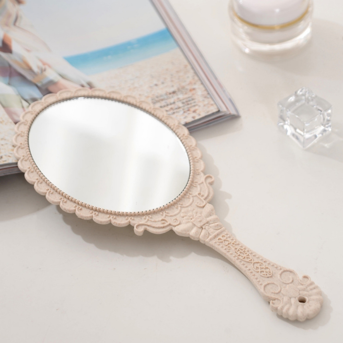 Ein Handspiegel auf einem Tisch mit einer Zeitschrift und Creme.