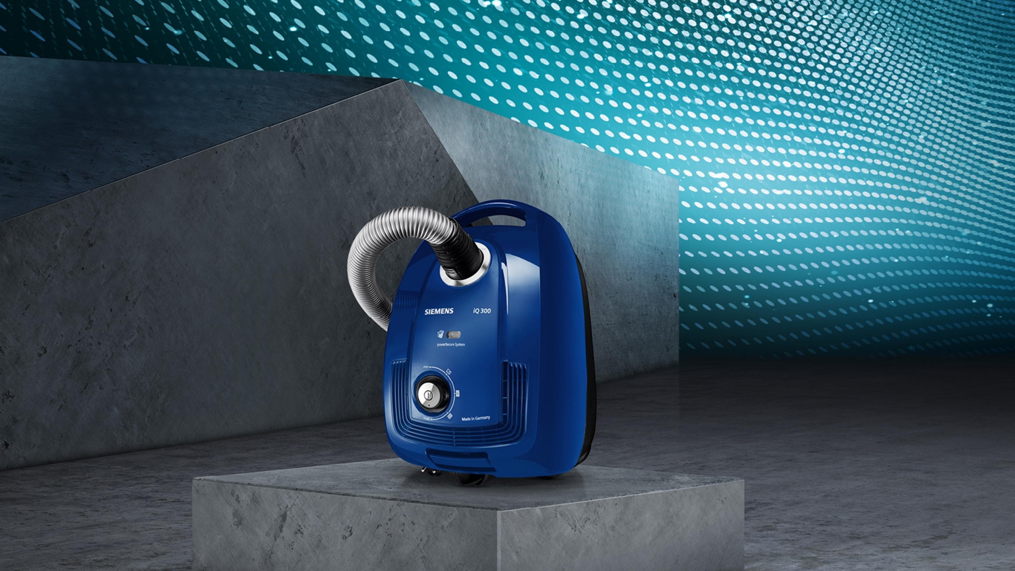 Niebieski odkurzacz Siemens na szarej platformie, z białym tłem i niebieskim wzorem.