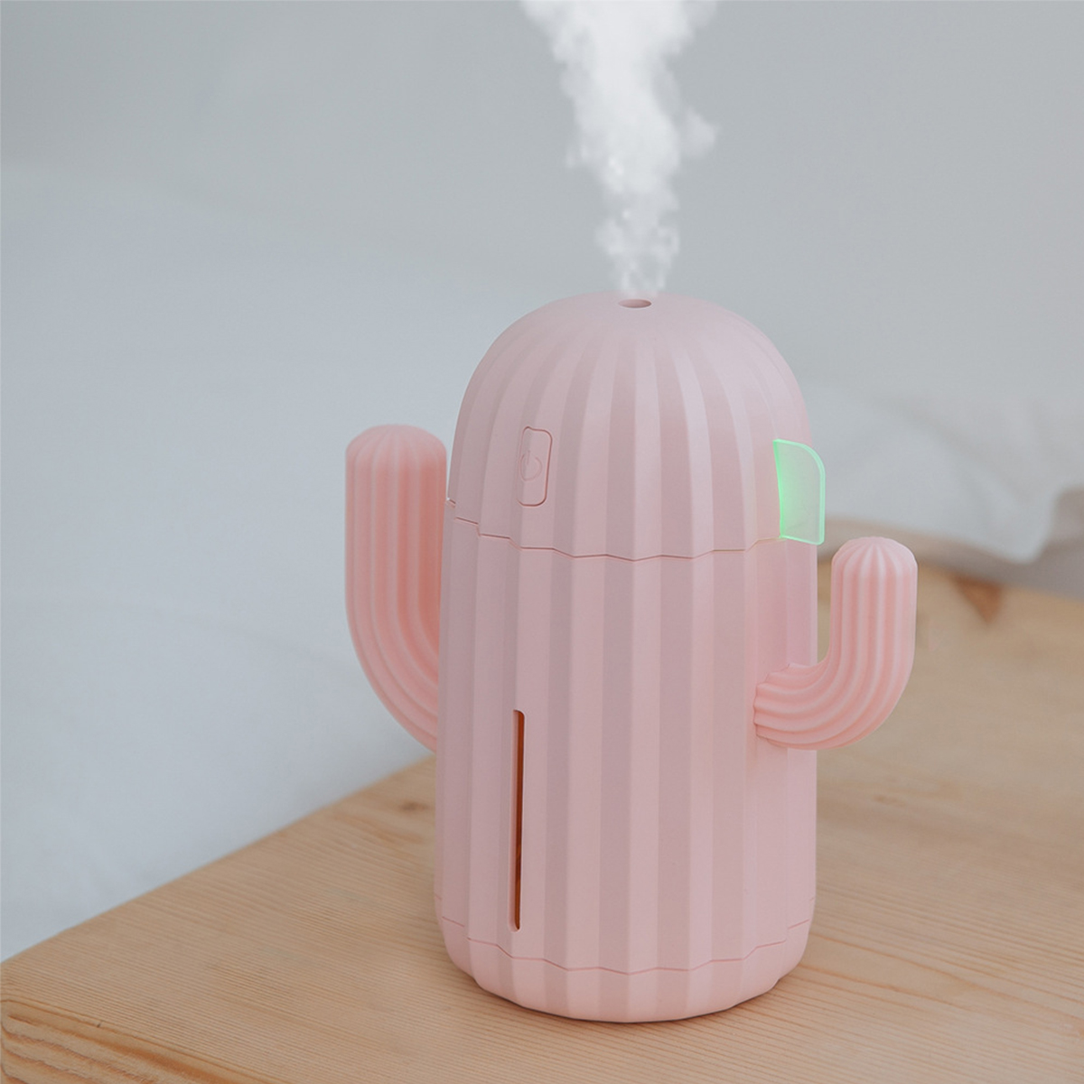 Ein rosa kaktusförmiger Luftbefeuchter, der Dampf abgibt, auf einer weißen Oberfläche platziert.