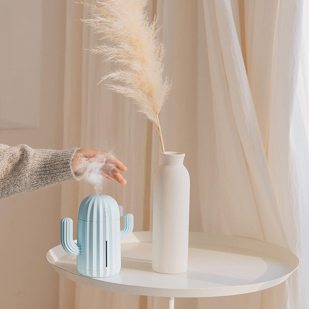Ein kaktusförmiger Luftbefeuchter mit Dampf, zusammen mit einer Vase mit Pflanze.