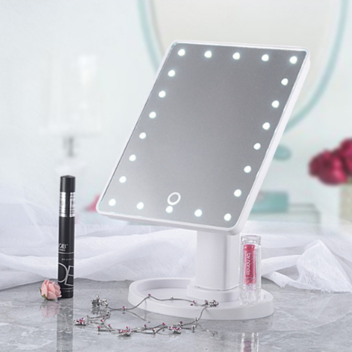 Beleuchteter Schminkspiegel mit Make-up-Artikeln auf weißer Oberfläche.