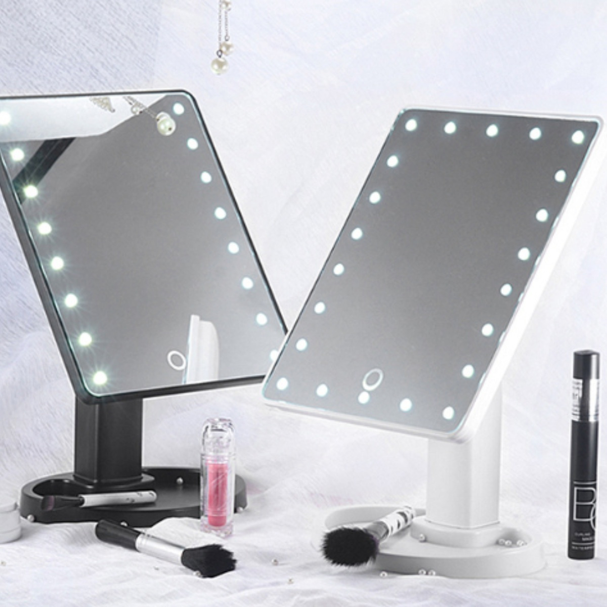 Zwei beleuchtete Schminkspiegel. Jeder Spiegel hat eine Ablage mit Make-up-Produkten.