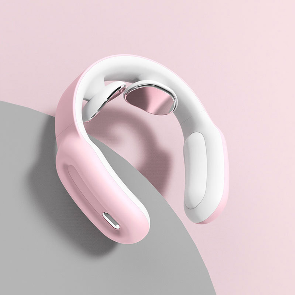Ein rosa-weißer Nackenmassagegerät auf einer rosa-grauen Oberfläche.
