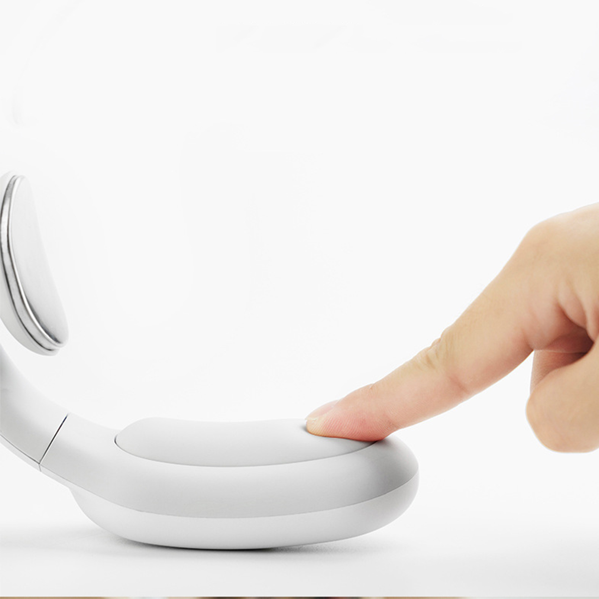 Hand drückt Knopf auf weißem Nackenmassagegerät. Weißer Hintergrund.