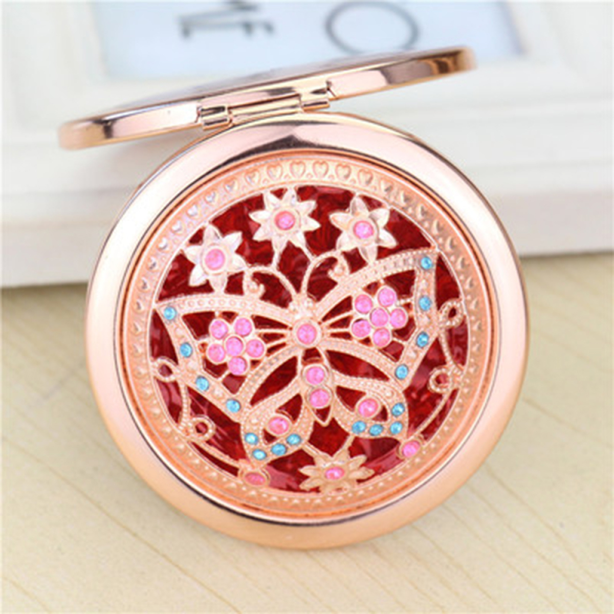 Runder, roségoldfarbener Kompaktspiegel mit Schmetterling- und Blumendesign.