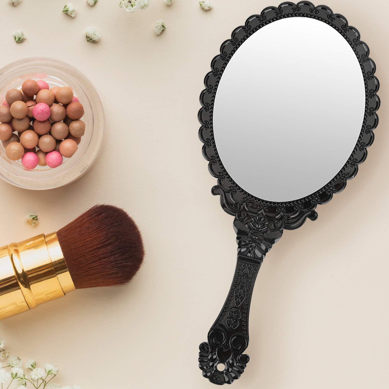Ein Schminktisch mit Handspiegel, Make-up-Pinsel und einem Tiegel mit Make-up-Kugeln.