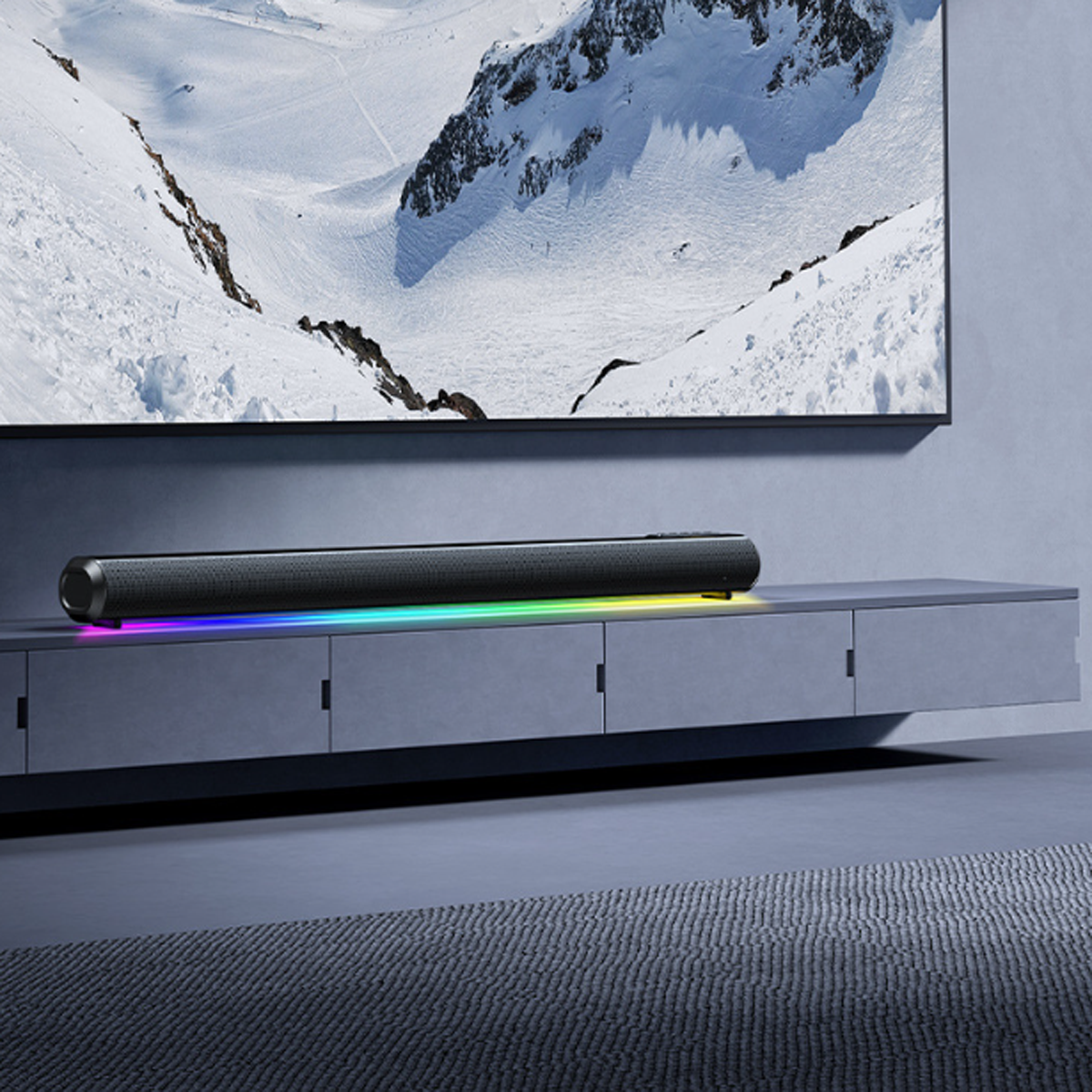 Eine schwarze Soundbar mit farbigem Lichtstreifen, montiert auf einem grauen Schrank.