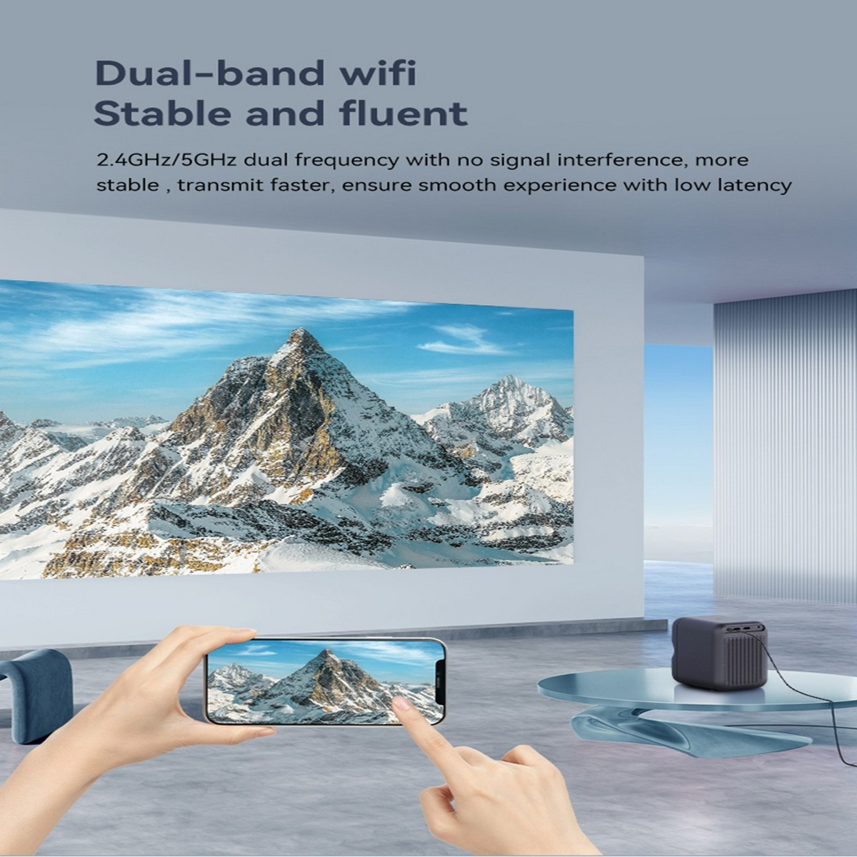Una persona sostiene un teléfono, señalando una escena de montaña en una pantalla grande, con un pequeño dispositivo.