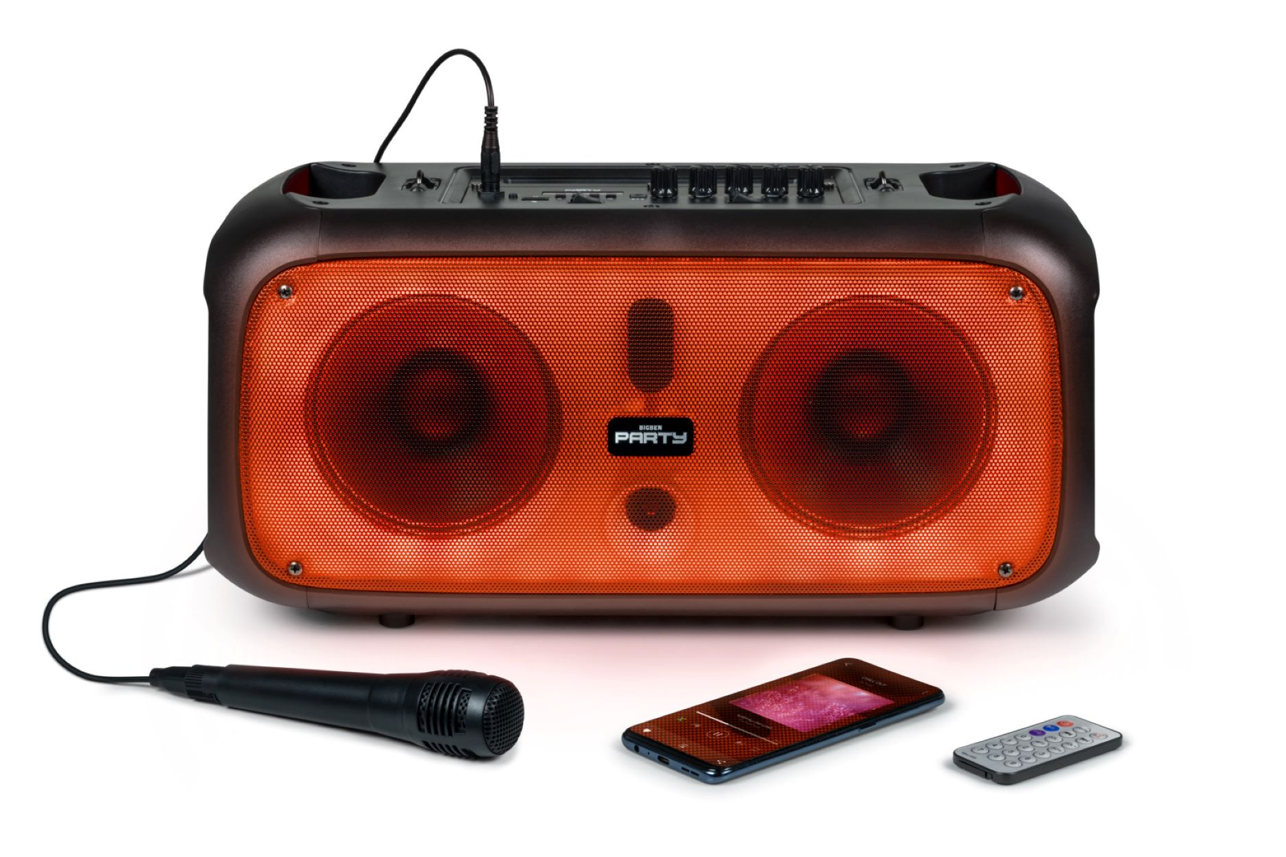 Czarno-pomarańczowy głośnik z mikrofonem, telefonem i pilotem na białej powierzchni.