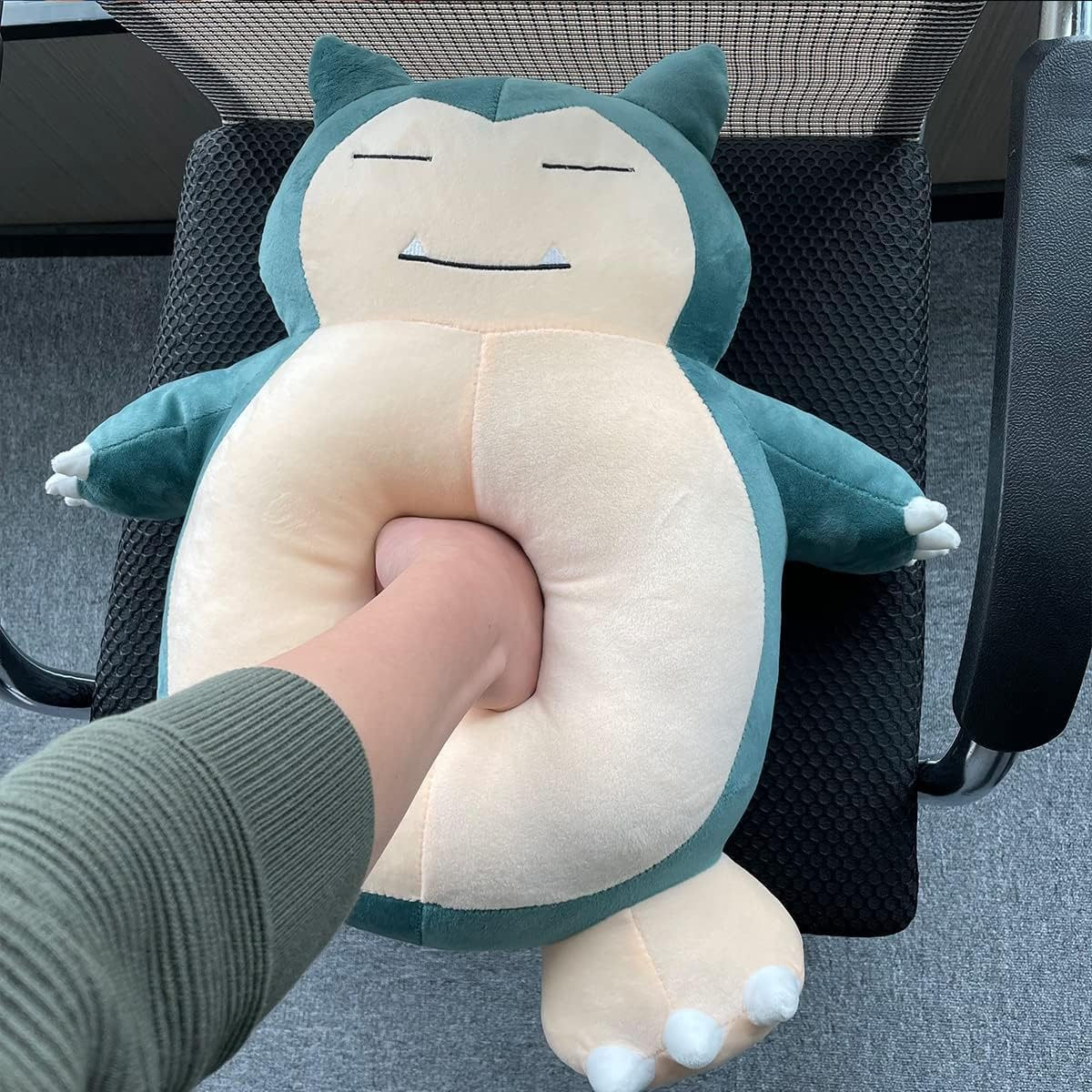 Eine Person drückt ein Plüschtier von Snorlax, mit einer Hand im Bauch des Plüschtiers.
