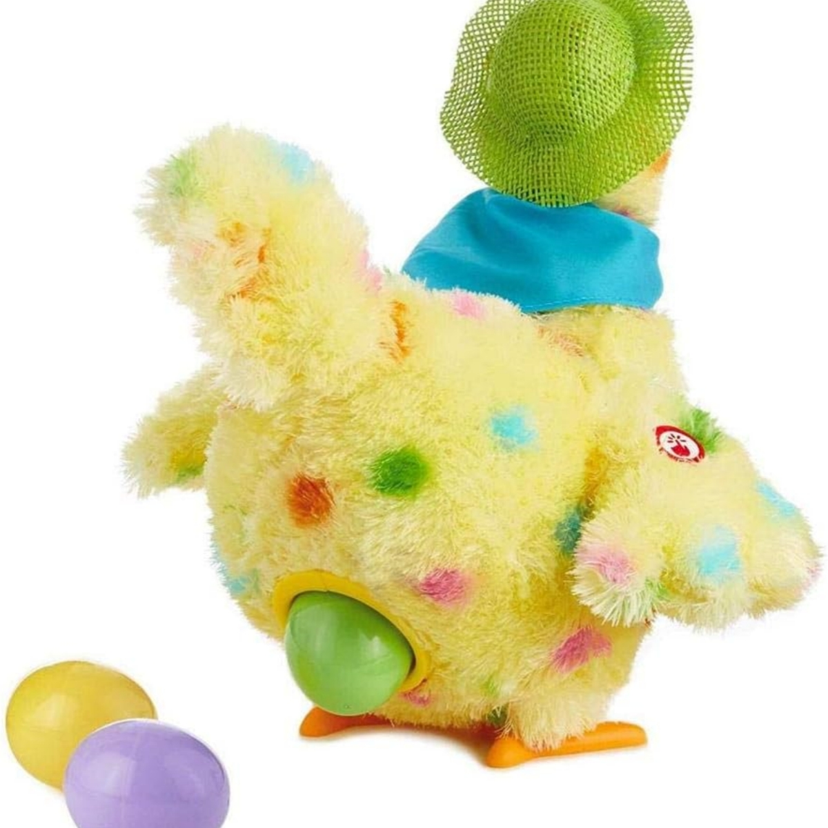Gelbes Spielzeug-Huhn mit Hut. Drei farbige Eier daneben, weißer Hintergrund.