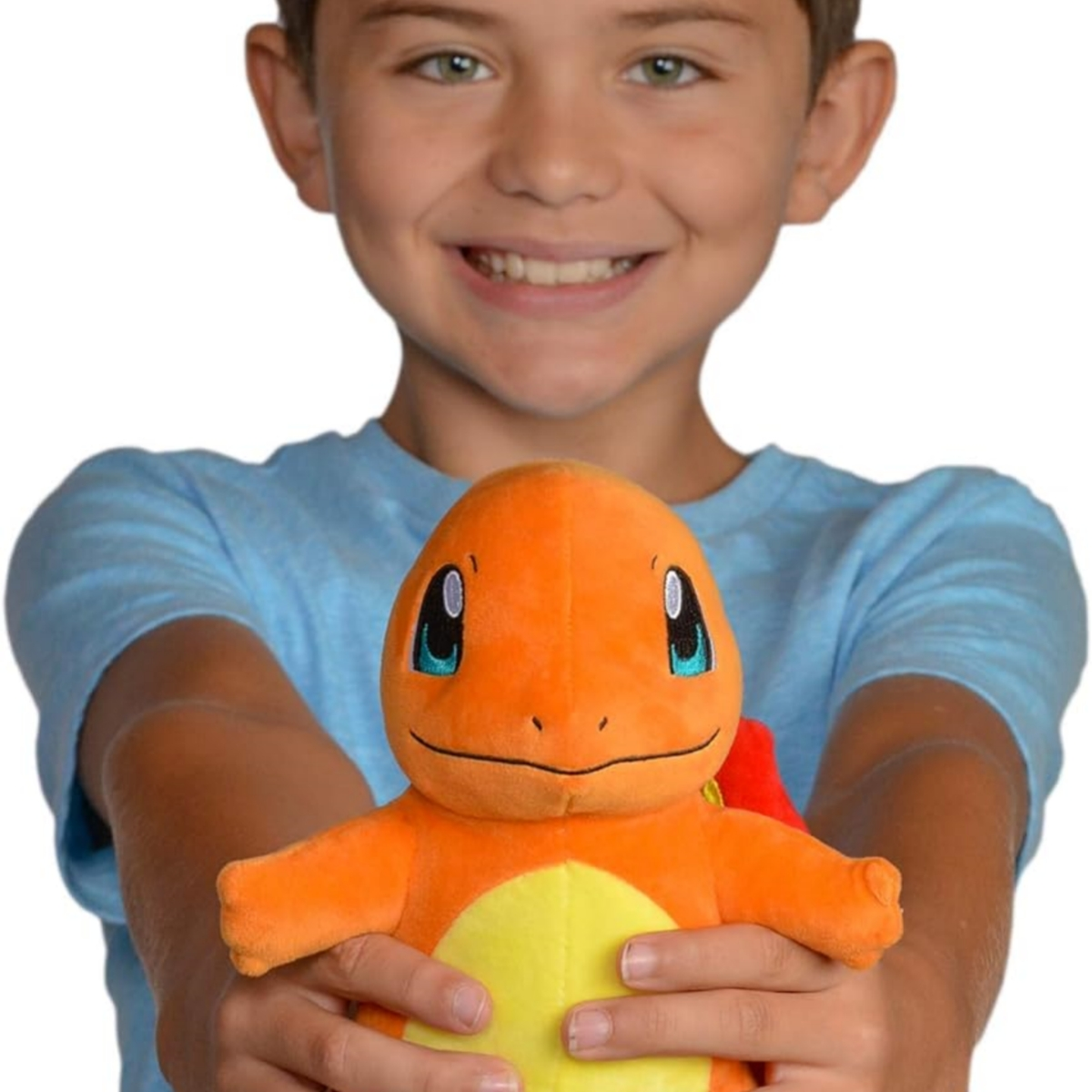 Ein Junge hält ein Charmander-Plüschtier und lächelt in die Kamera.