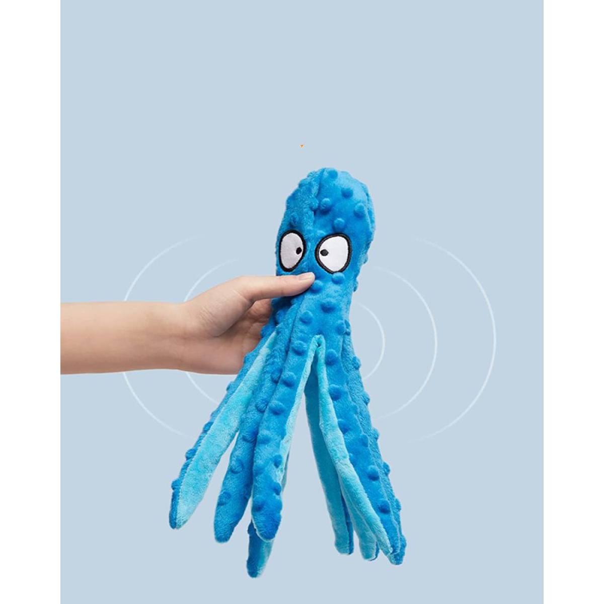 Ein blaues Plüsch-Oktopus-Spielzeug, gehalten von einer Hand vor hellblauem Hintergrund.