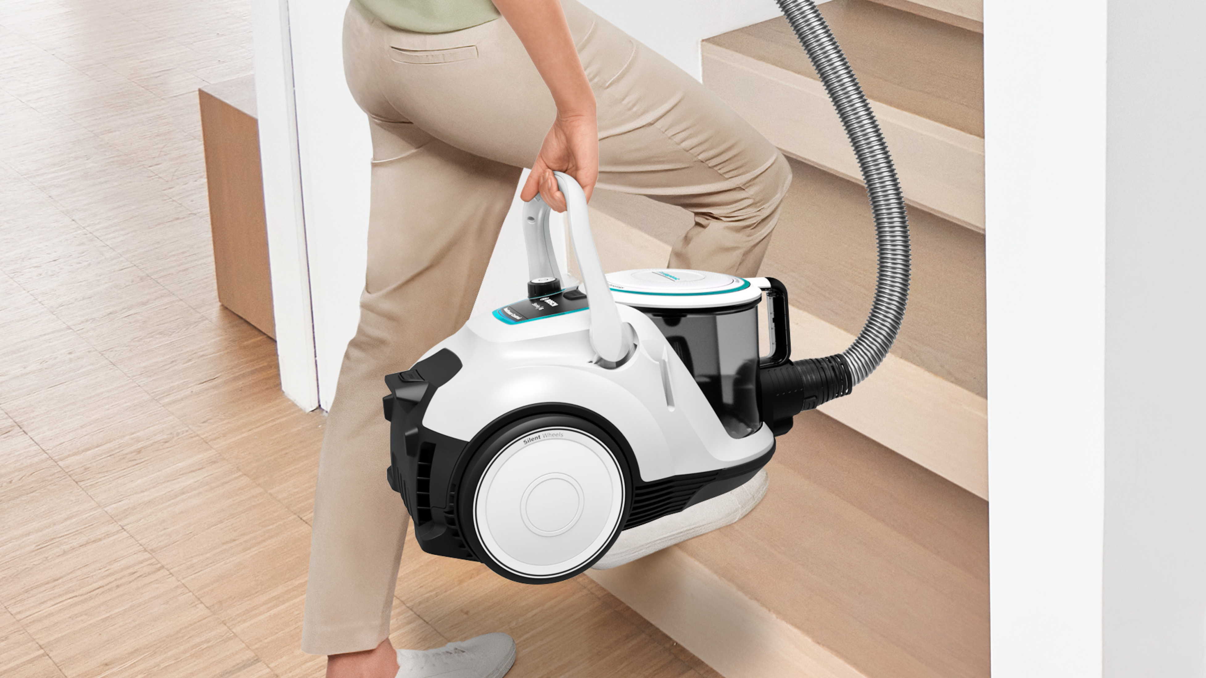 Osoba niesie biało-niebieski odkurzacz po schodach.