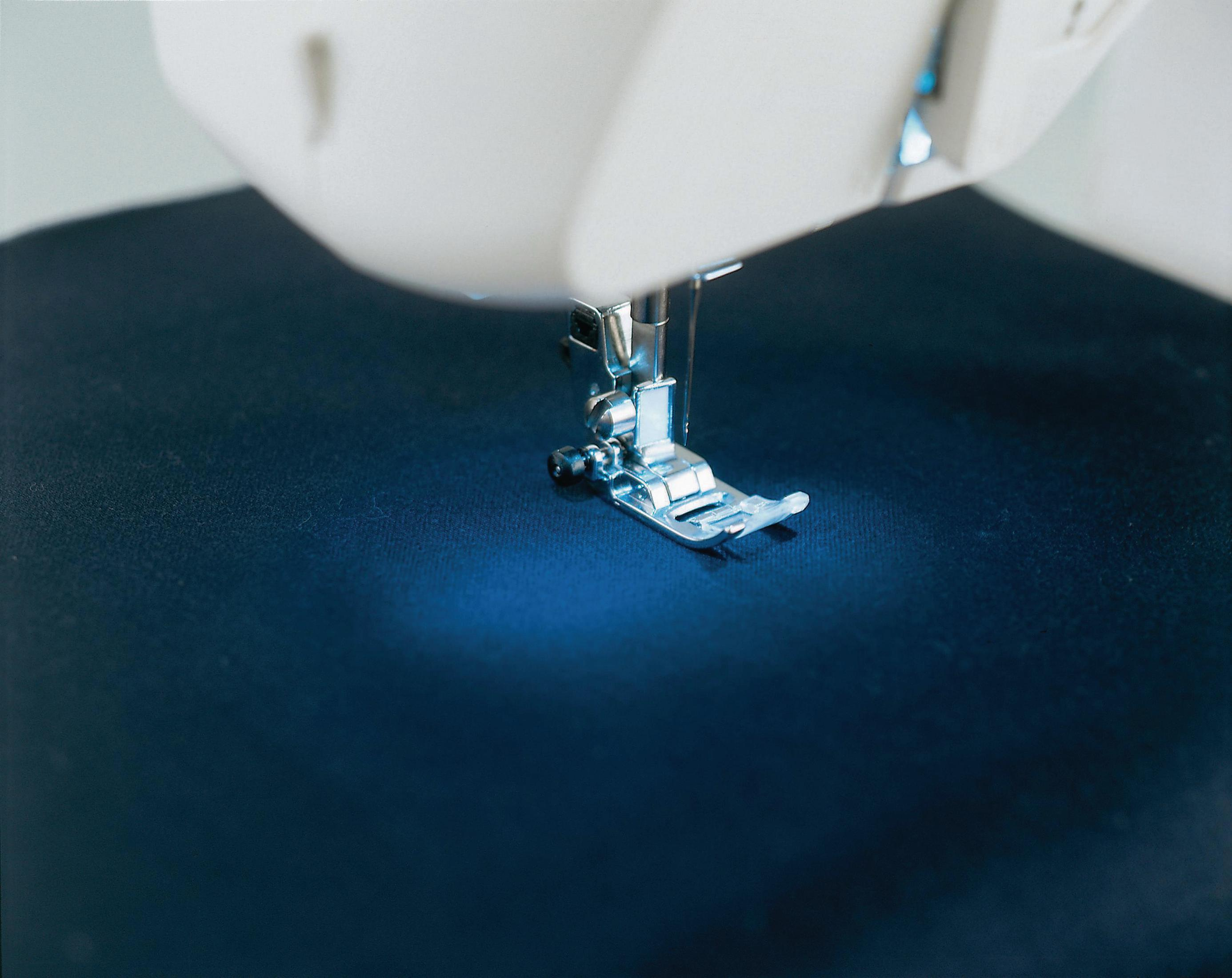 Zbliżenie igły maszyny do szycia i czarnej tkaniny. Ostrość na igle.