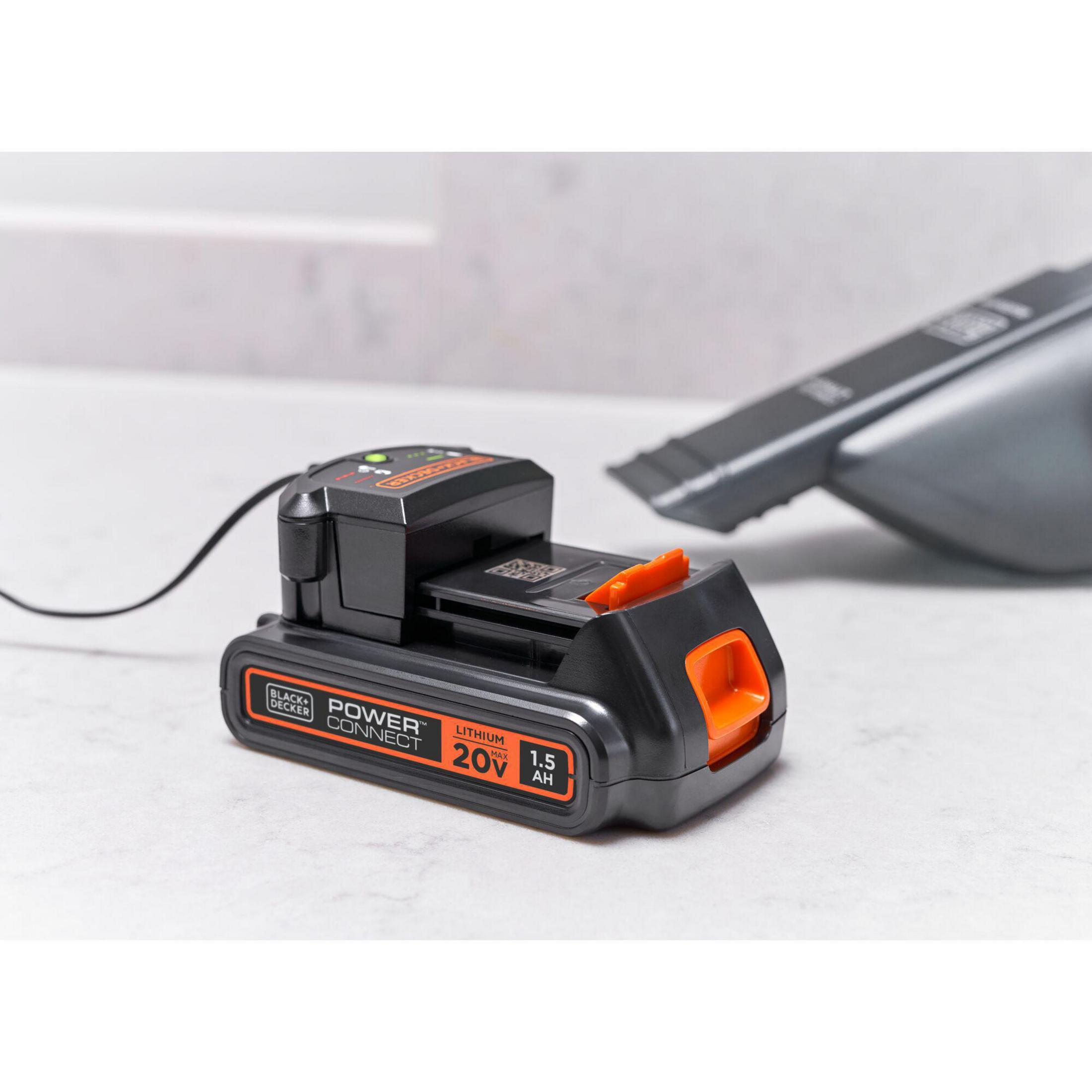 Ein schwarz-oranges Black+Decker-Akkuladegerät mit eingelegtem Akku. Es steht auf einer weißen Oberfläche.