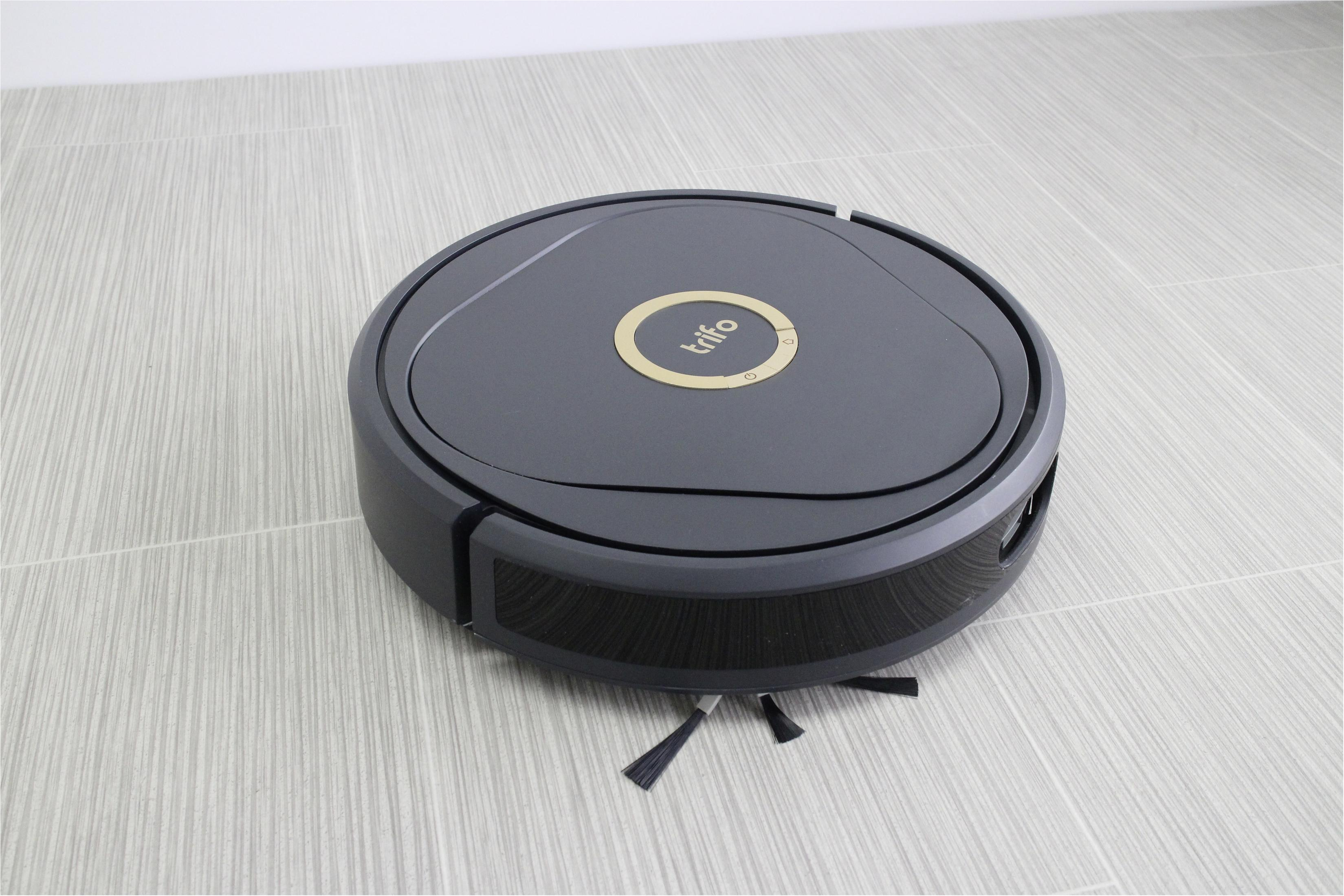 Czarny robot odkurzający Trifo na podłodze z płytek, widok z boku.