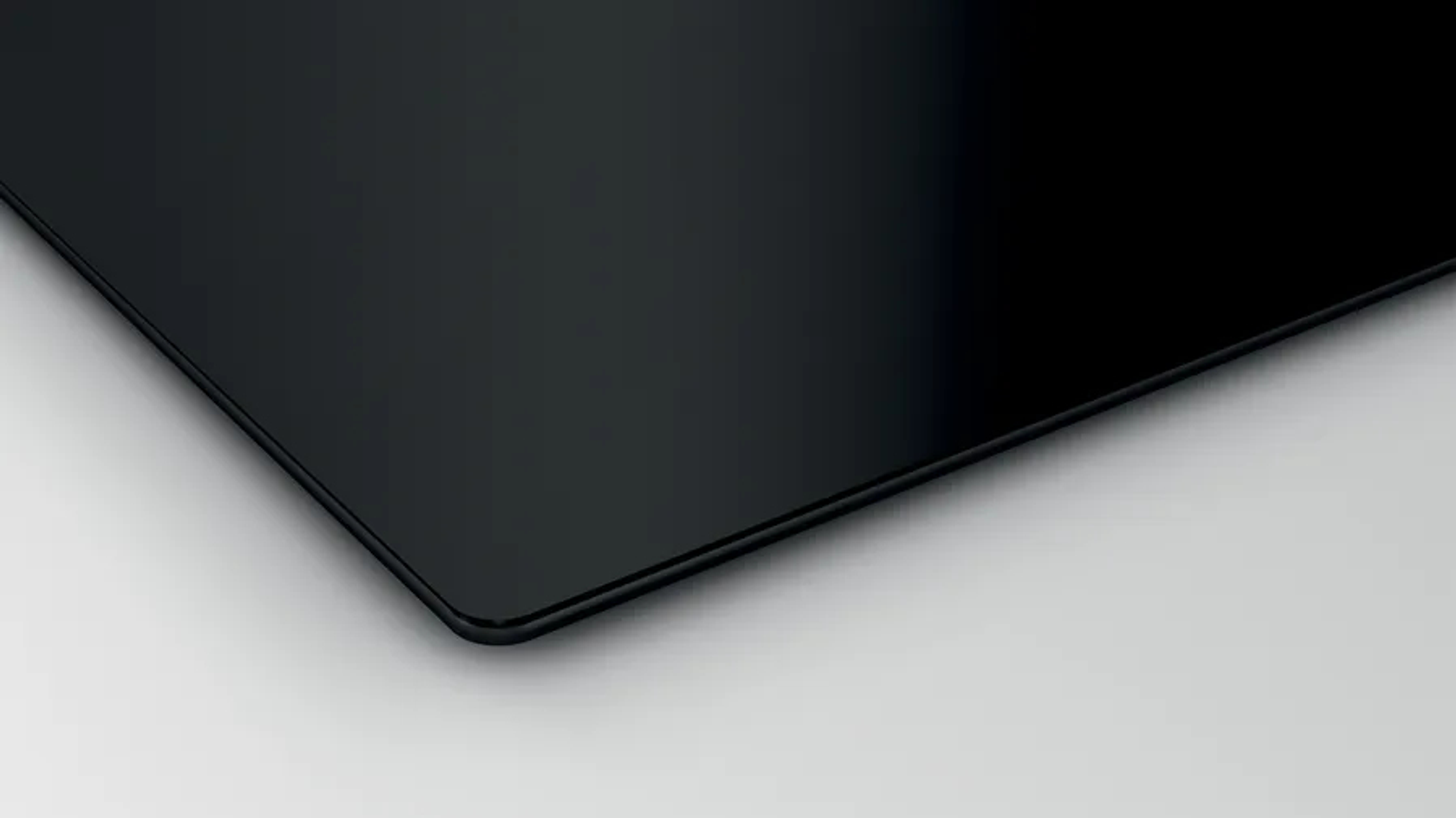 Zbliżenie eleganckiej, czarnej, szklanej płyty indukcyjnej na białej powierzchni.