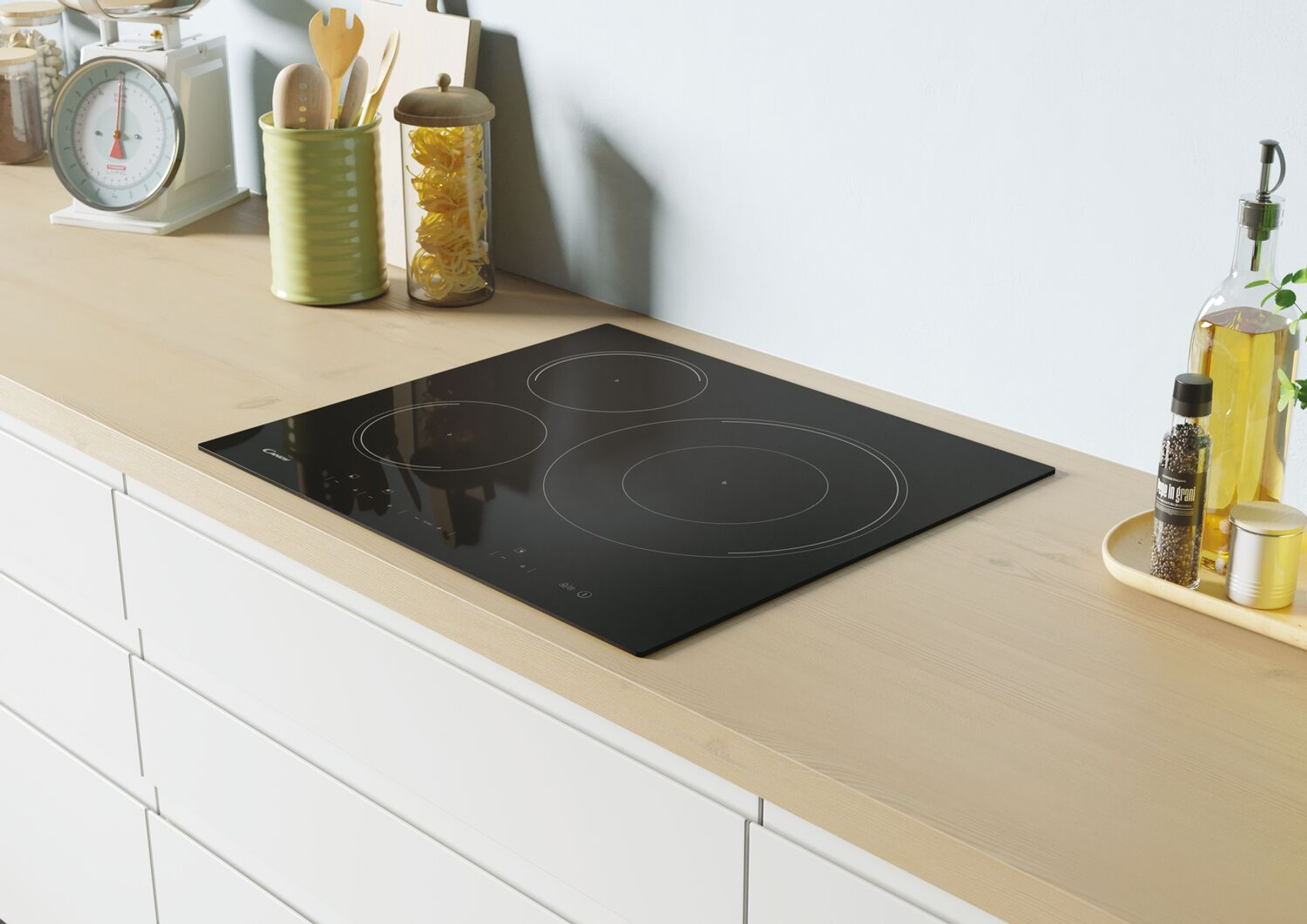 Czarna płyta indukcyjna na drewnianym blacie. Widoczne trzy okrągłe strefy gotowania. Białe szafki w tle.