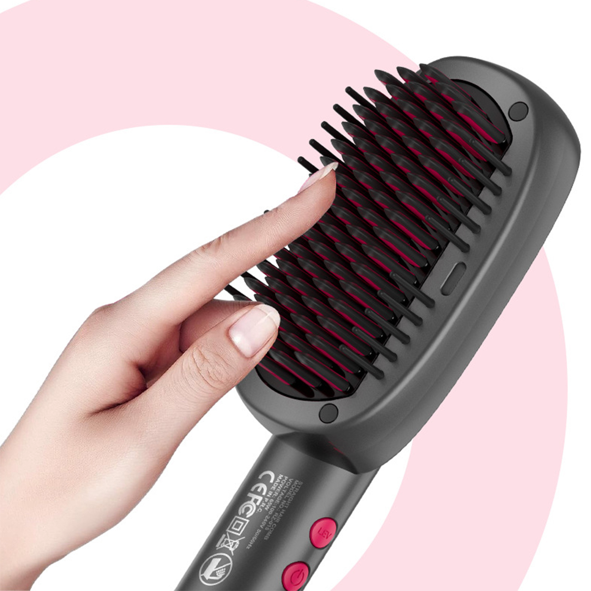 Eine Hand benutzt eine schwarze, graue und rote Haarglättungsbürste. Die Bürste befindet sich auf einem rosa Farbverlaufshintergrund.