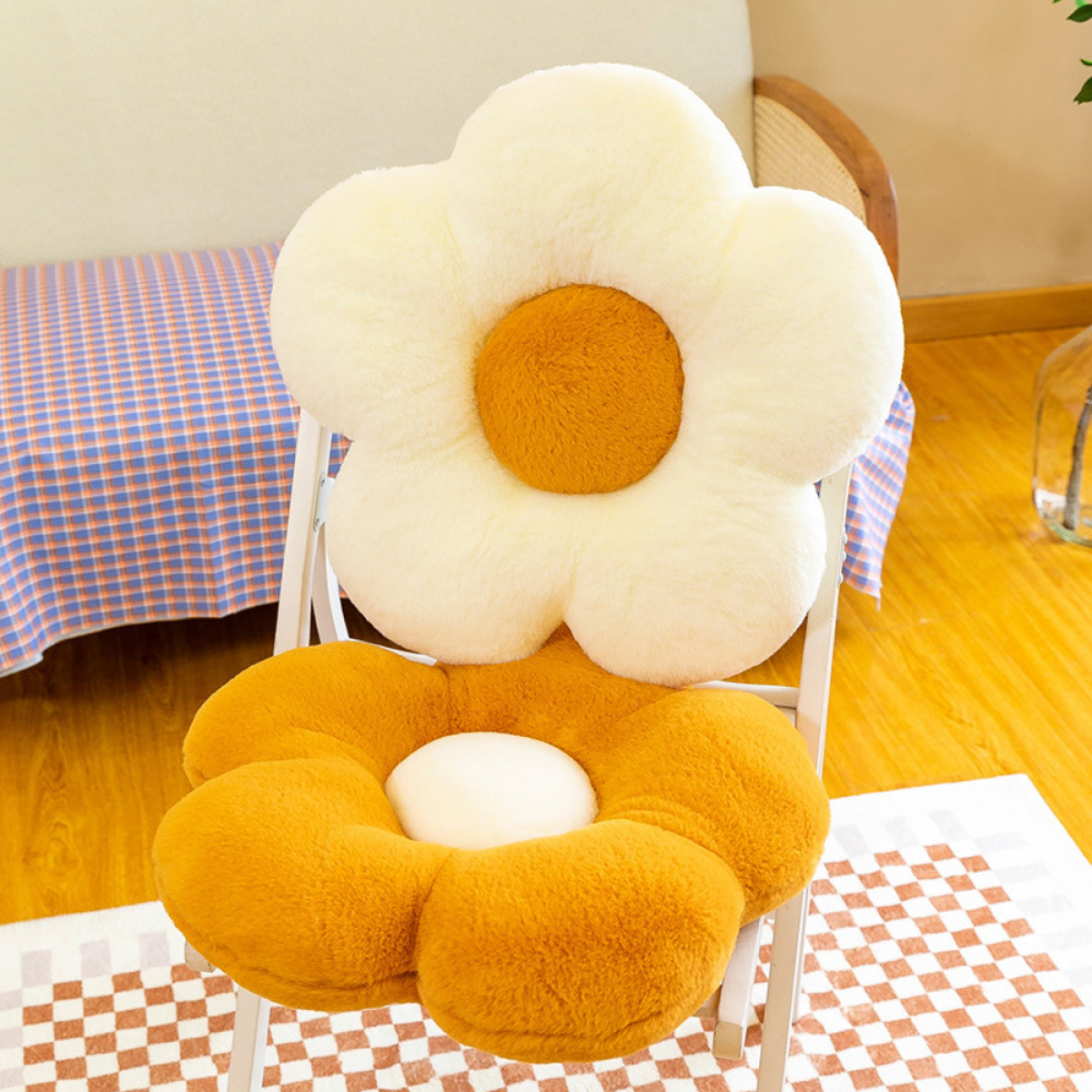 Blumenförmige Kissen auf einem weißen Stuhl. Im Hintergrund ein Bett und Holzboden.