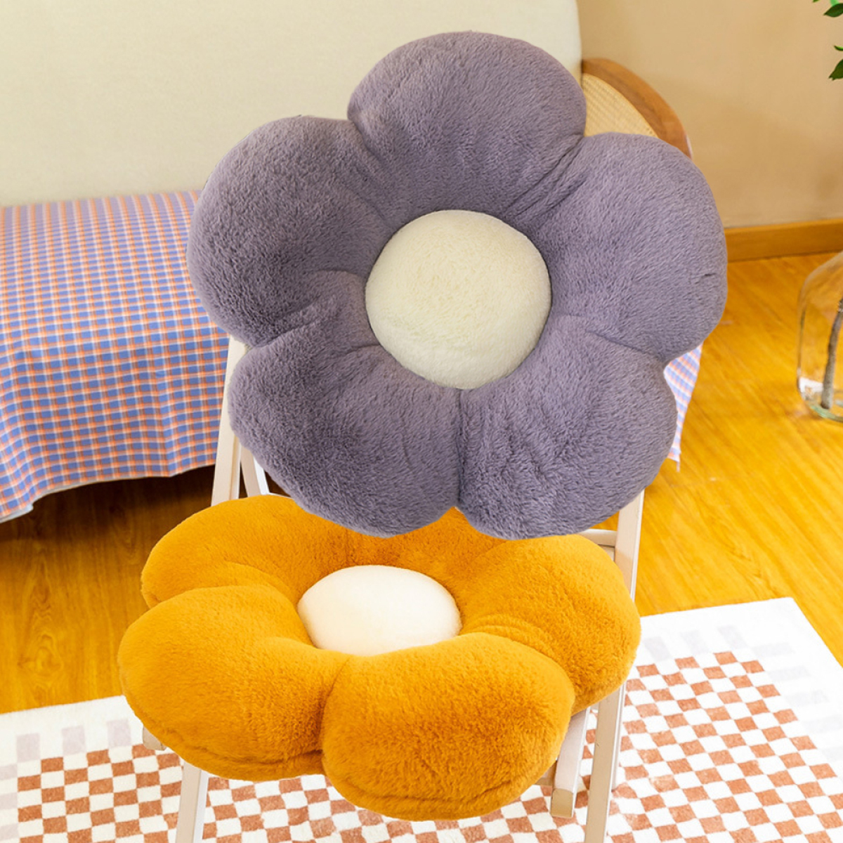 Zwei blumenförmige Kissen, eines lila, eines orange, auf einem Stuhl.