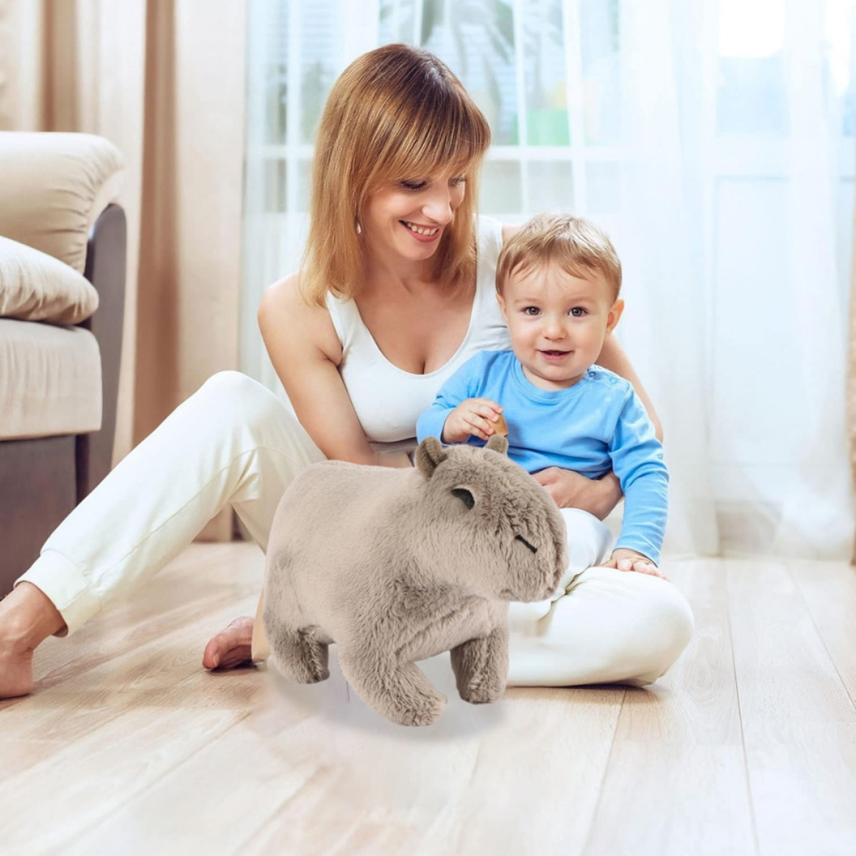 Eine Mutter und ein Baby sitzen mit einem Stofftier auf dem Boden. Das Baby lächelt und hält das Spielzeug.