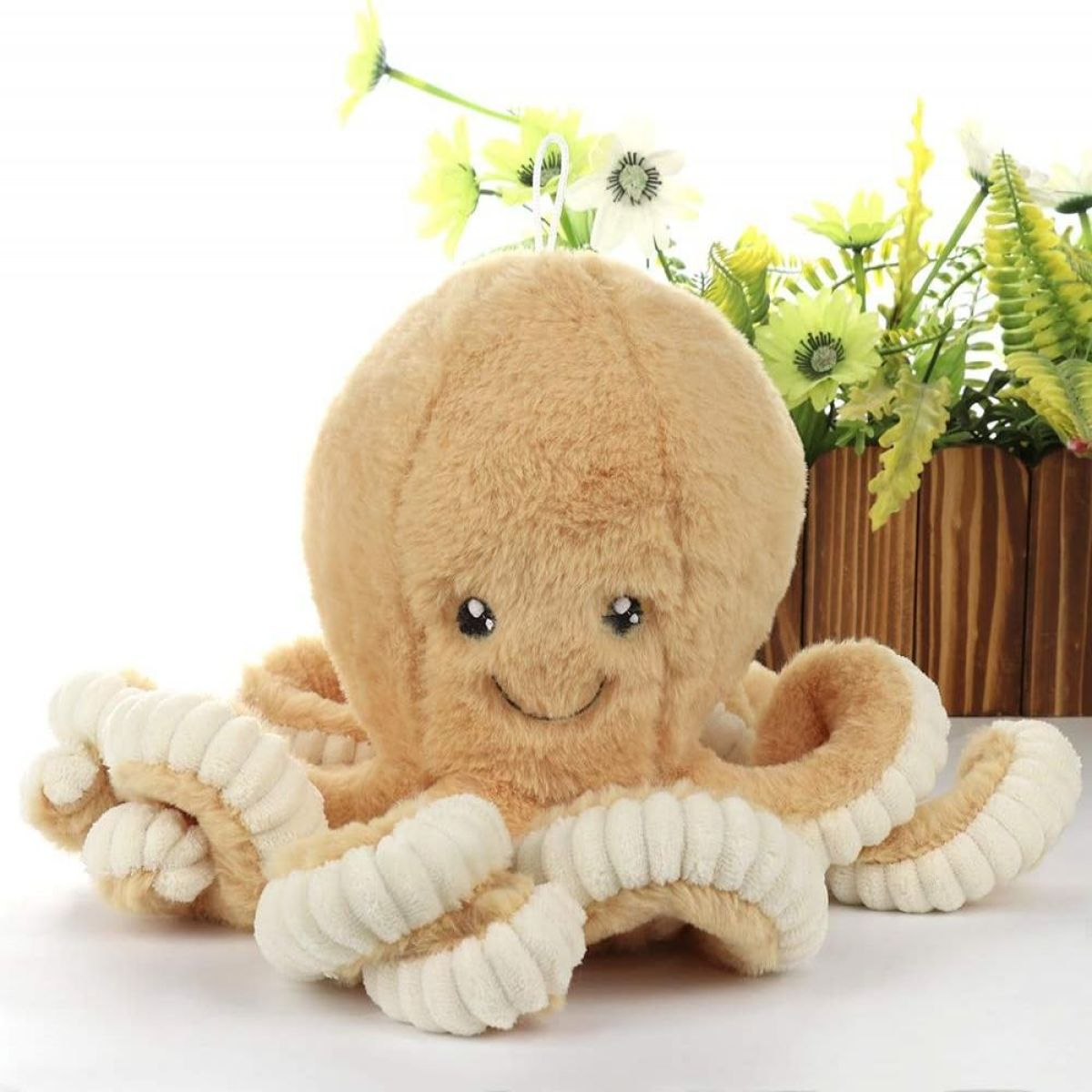 Ein Plüsch-Oktopus-Spielzeug in Beige, mit einem lächelnden Gesicht und mehreren Tentakeln.