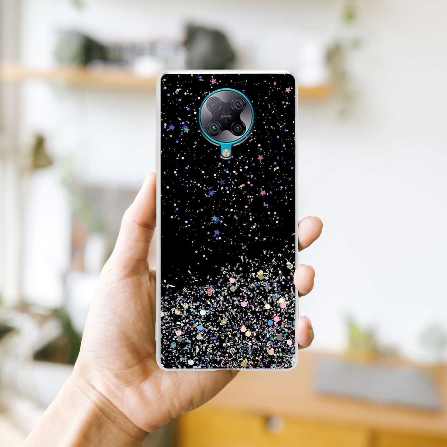 Mano che tiene una custodia per telefono con sfondo nero con glitter e piccole stelle.