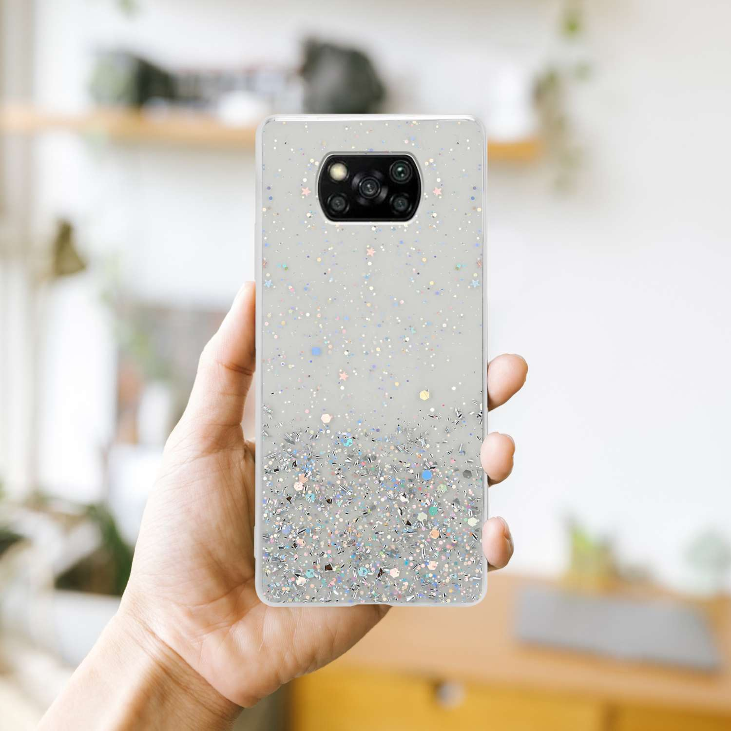 Una mano che tiene una custodia per telefono con glitter e un retro decorato.