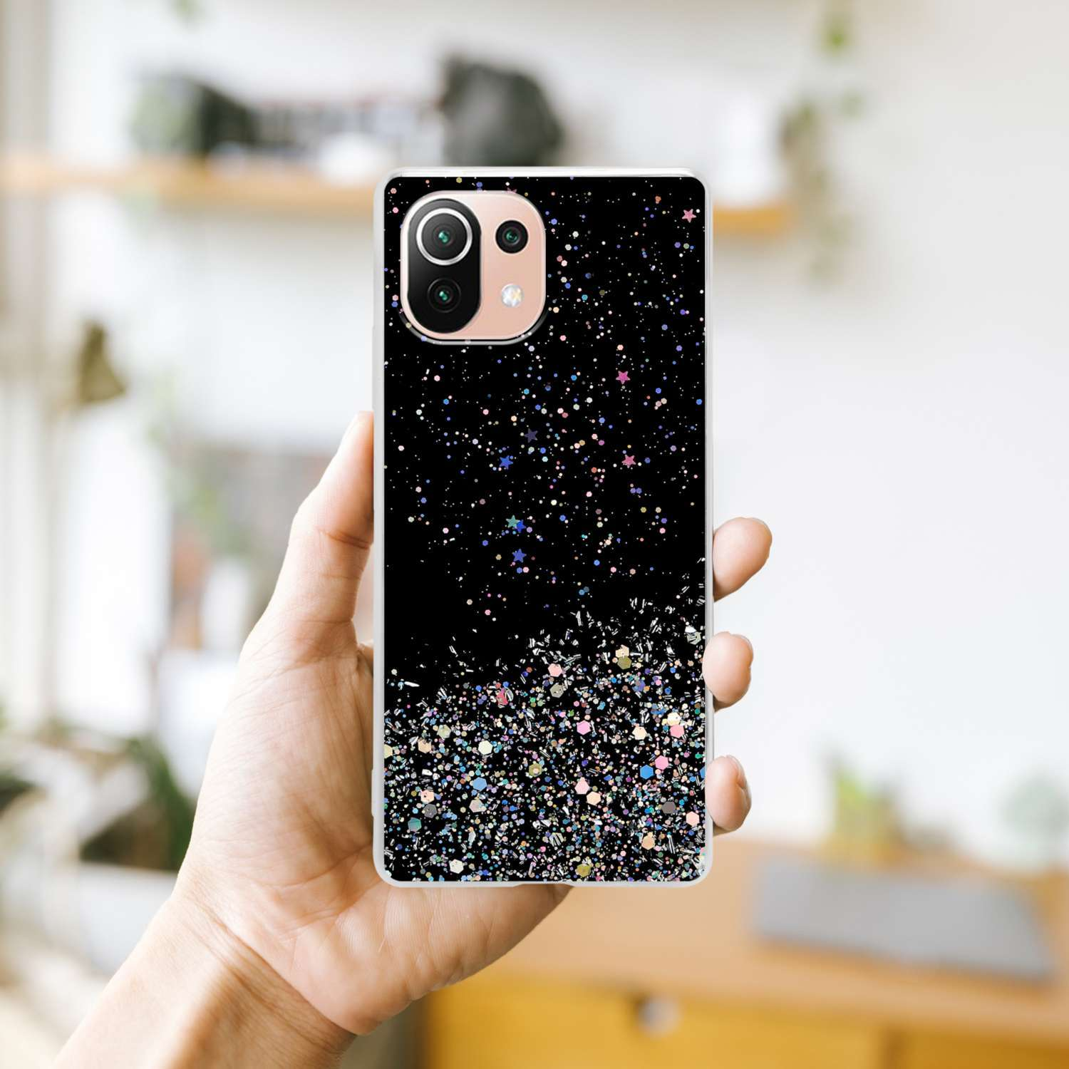 Hand hält eine Handyhülle mit schwarzem Glitzerdesign. Das Design verläuft von Glitzer zu Schwarz.