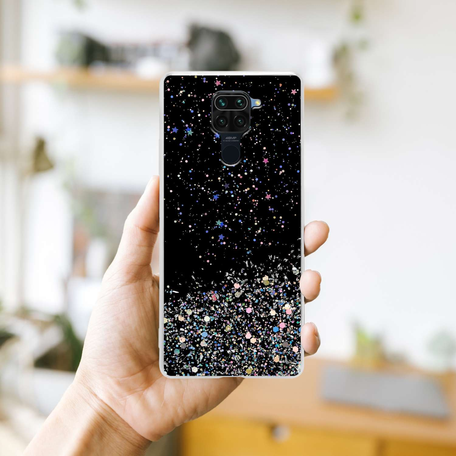 Una custodia per telefono con un design glitter nero. La custodia è tenuta in mano.