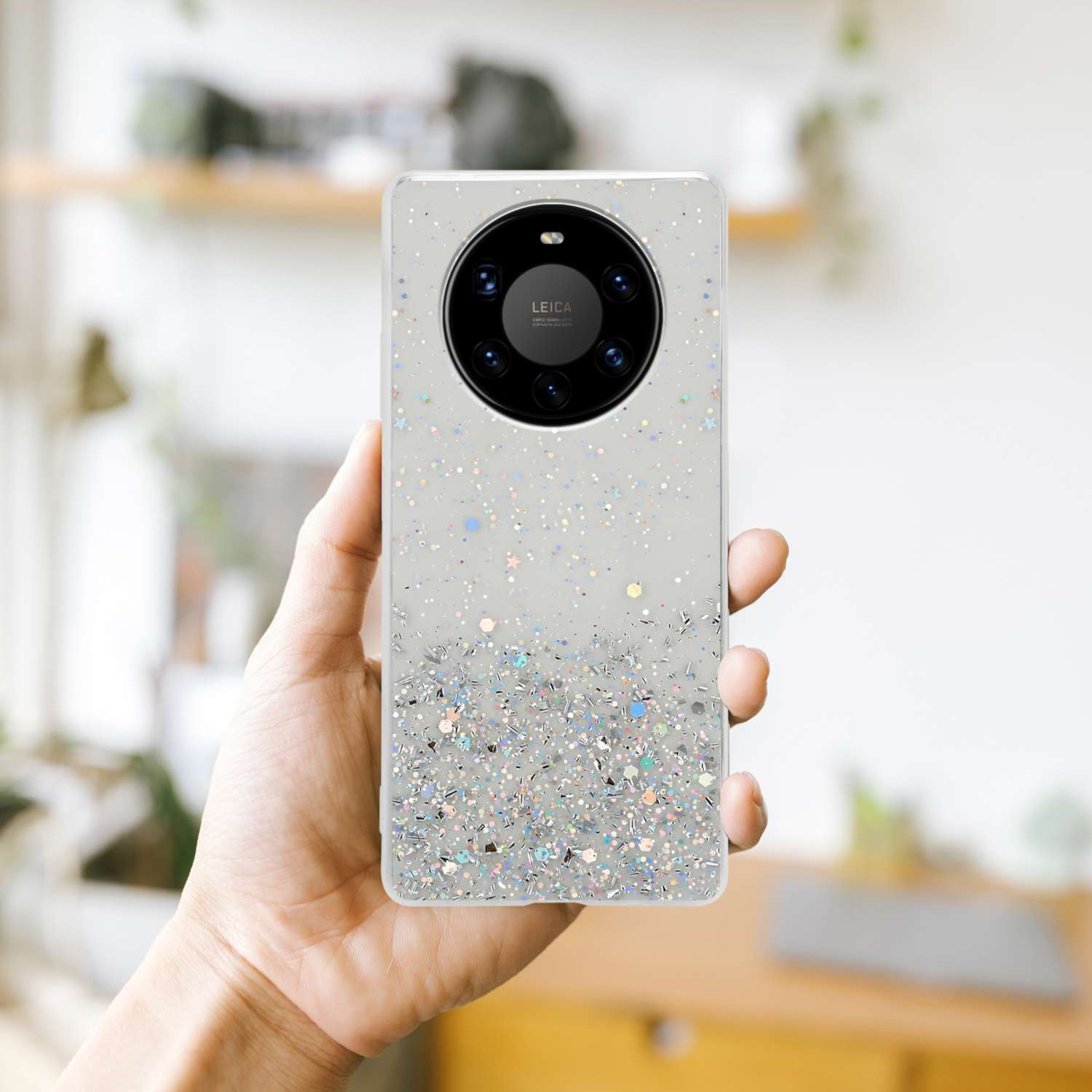 Die Hand einer Person hält ein Telefon mit einer glitzernden Hülle. Das Telefon hat eine Kamera.