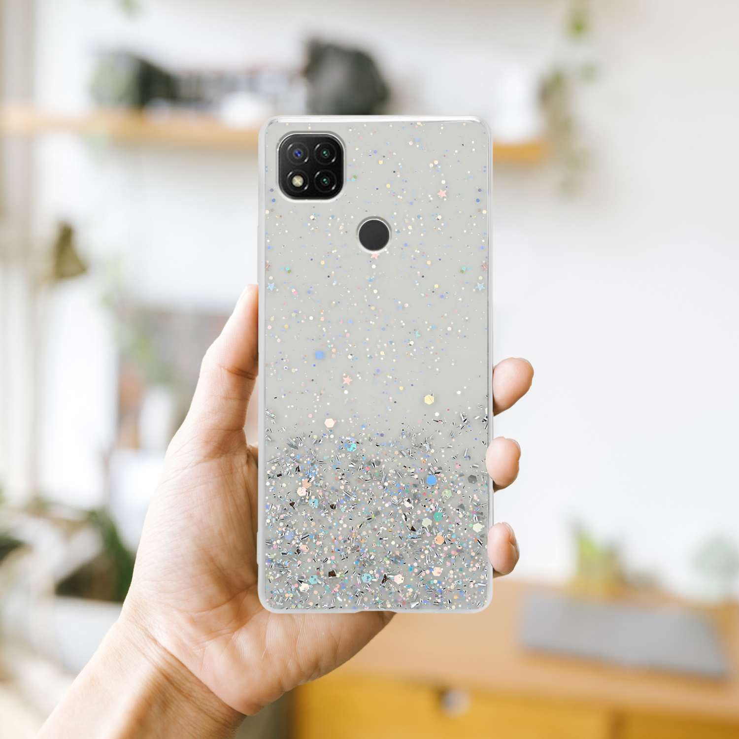 Una custodia per telefono con glitter, tenuta in mano. Ha una fotocamera e uno sfondo chiaro.