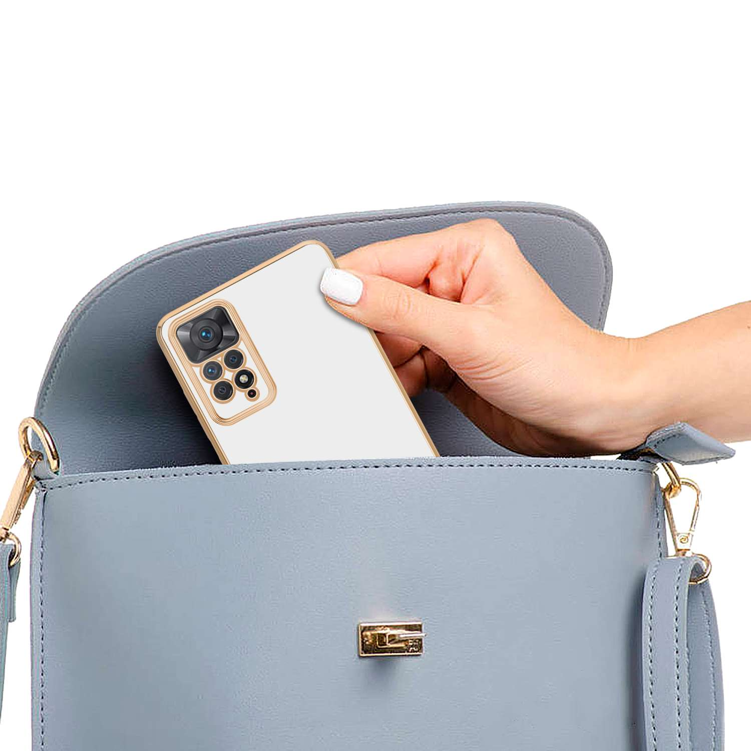 Una mano che mette un telefono bianco in una borsetta azzurra. Il telefono ha una cornice dorata.